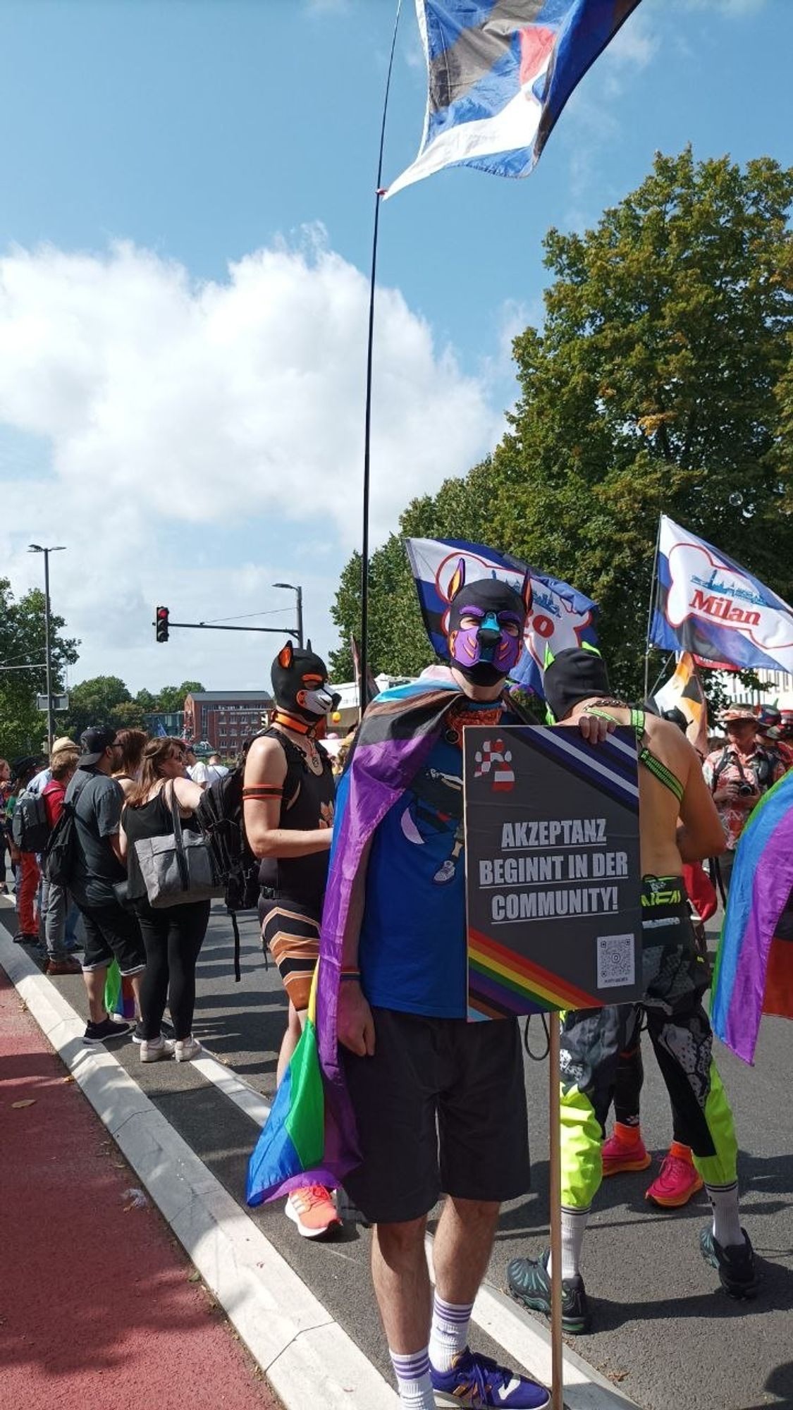 Kerbi mit Schild "Akzeptanz beginnt in der "Community" auf der Pride-Demo.