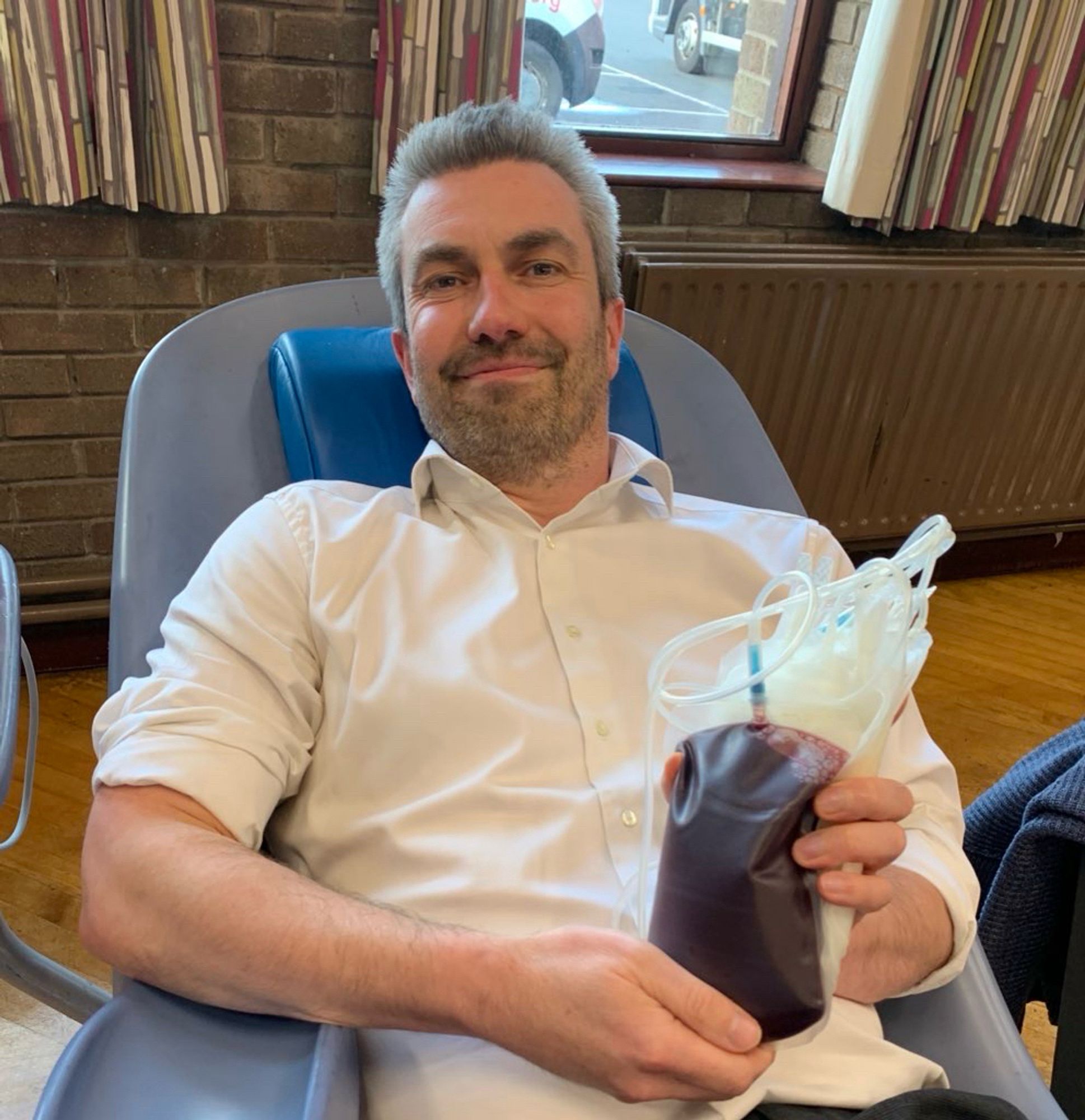 Photo of Danny holding a unit of donated blood at blood donation session.