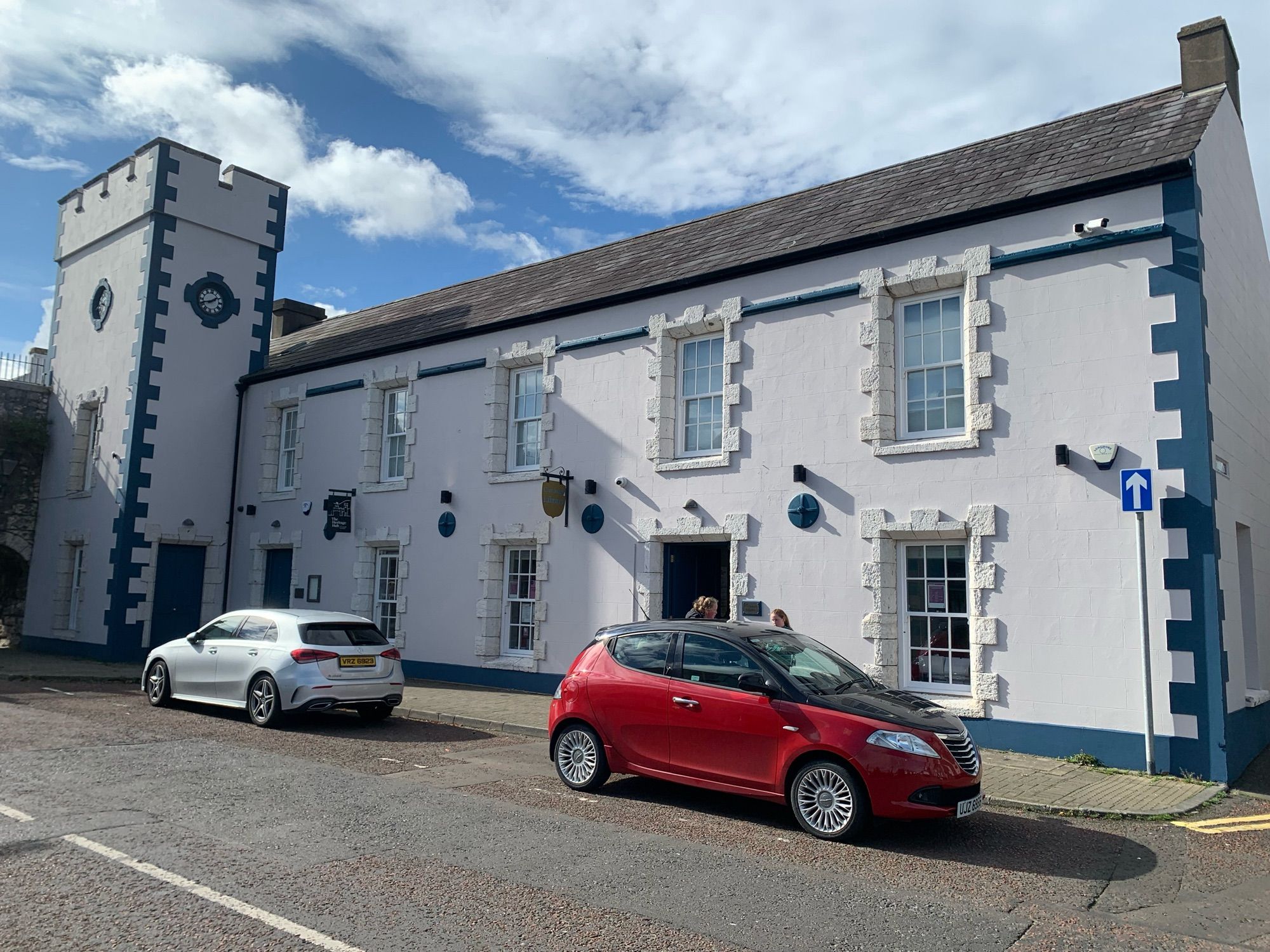 Photograph of Carnlough library. It’s a very old stone building with a clock tower on the left.