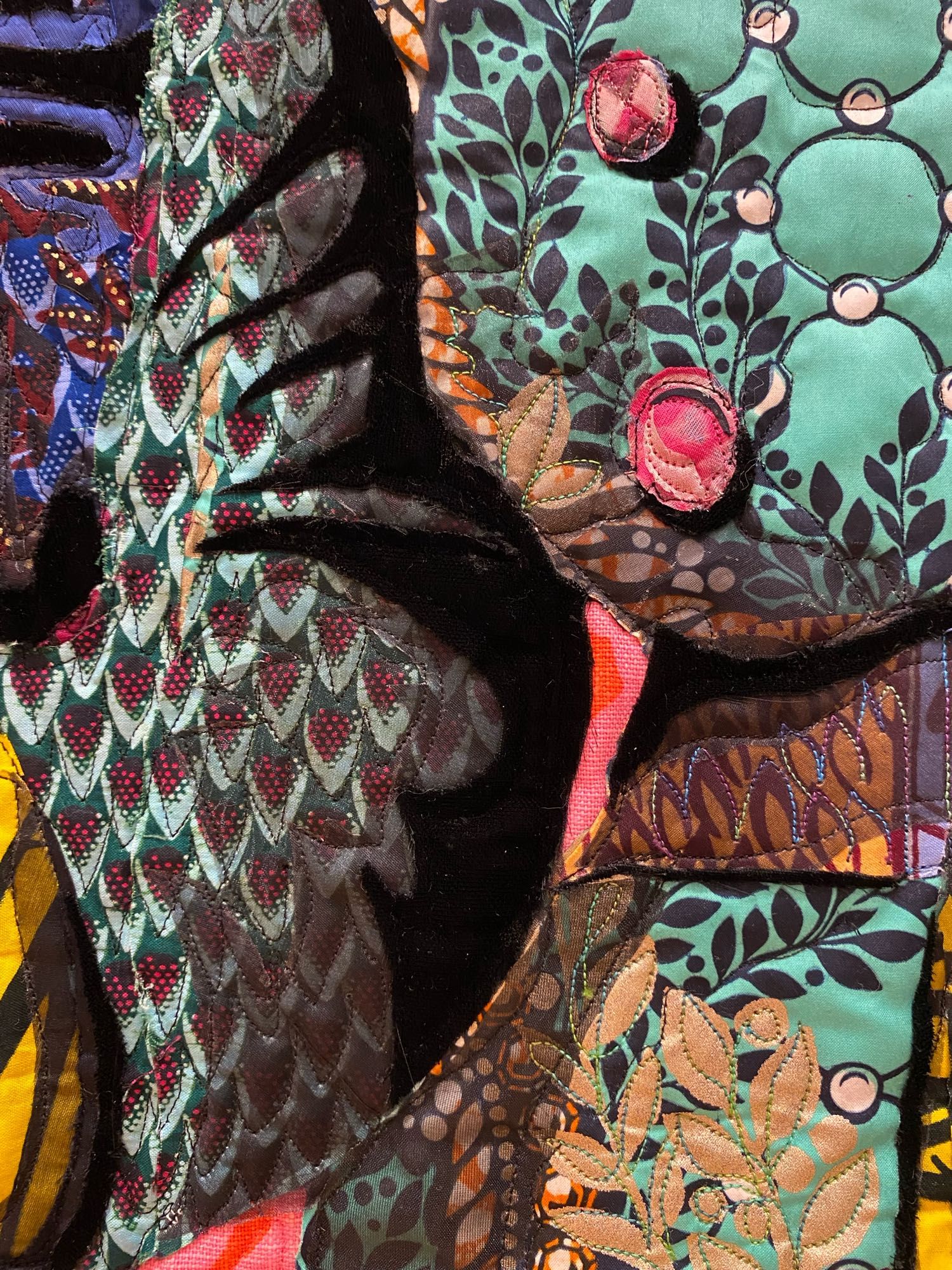 Detail the two side-by-side figures, depicted using layered, brightly colored, beautifully patterned fabrics.