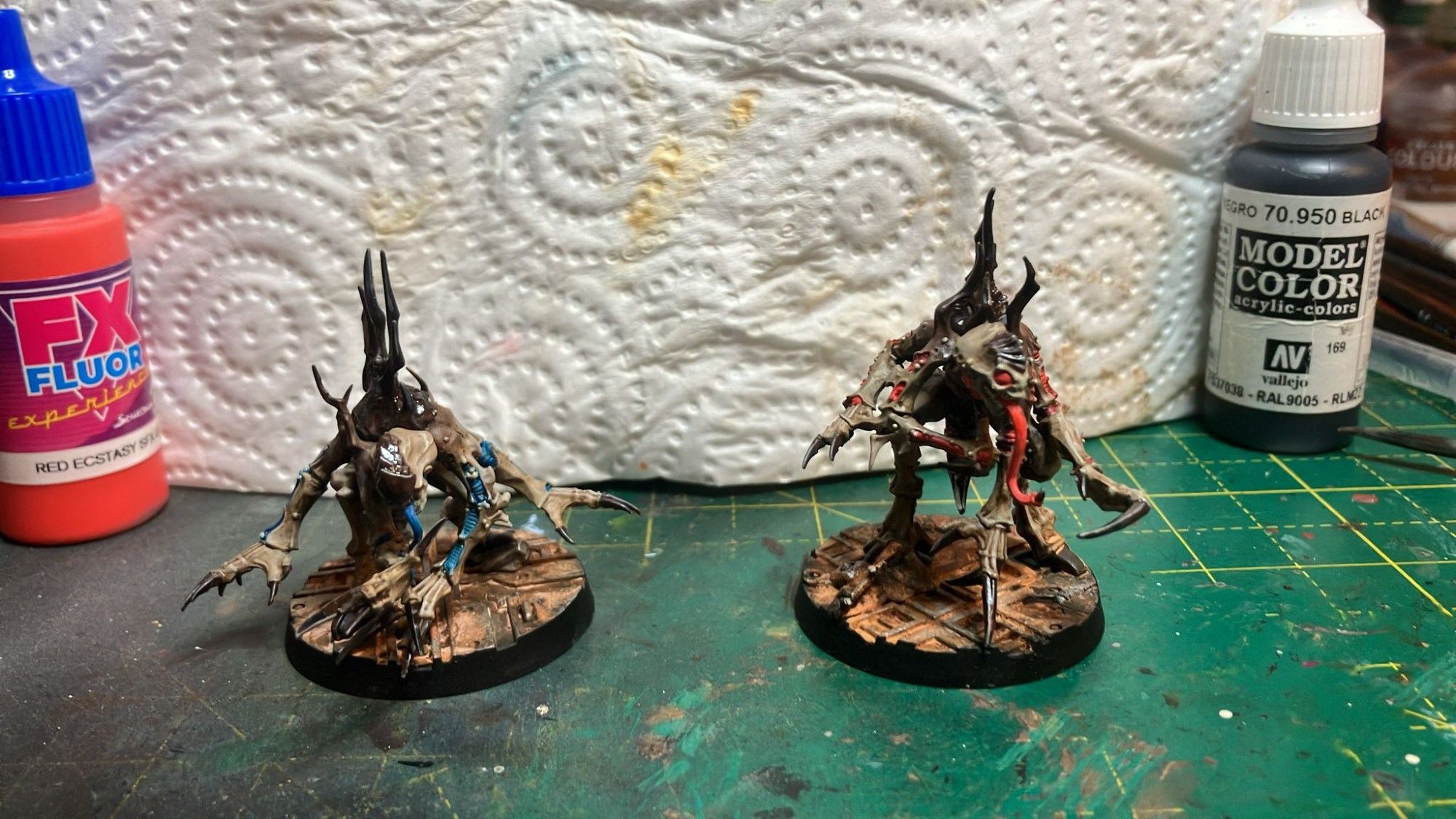 Two genestealers. Both with brown armour platers, bone skin. One with blue accents the other vibrant red.