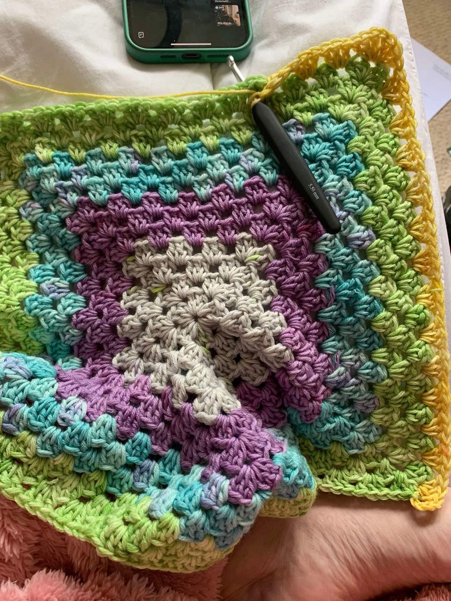 Crochet hexagon with grey, purple, blue, green, and yellow layers.