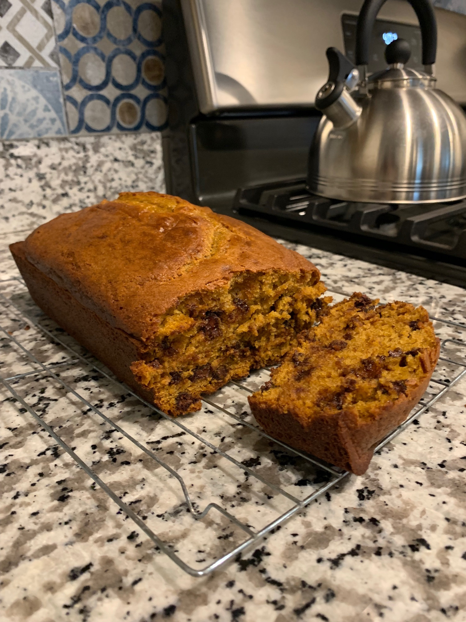 A loaf of pumpkin bread on a wire rack on the kitchen counter