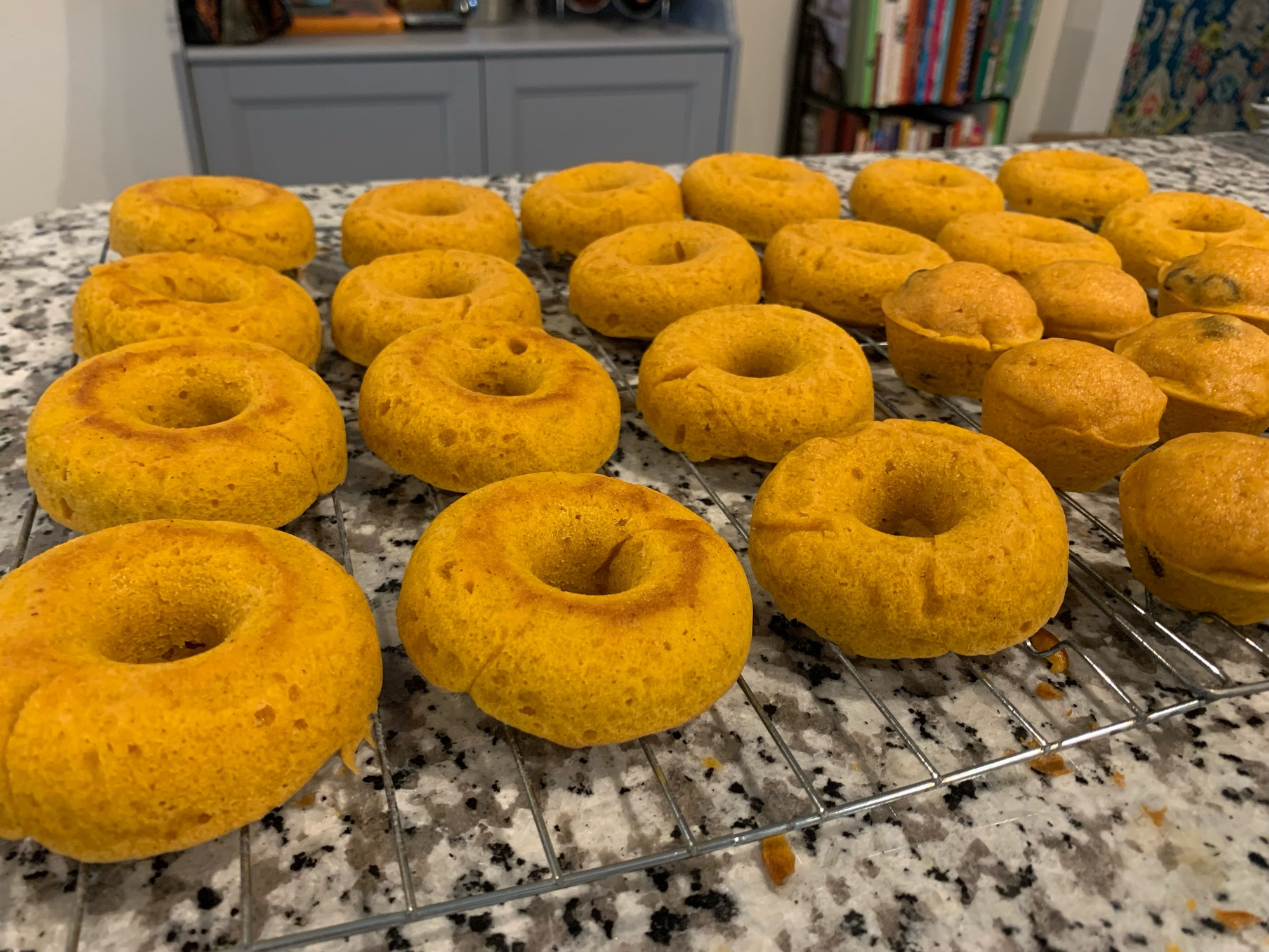 Pumpkin doughnuts and mini muffins on a cooling rack on the kitchen counter 