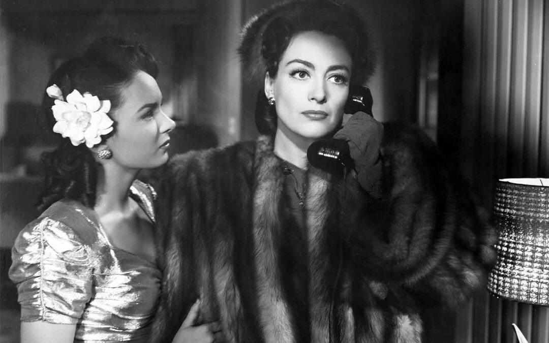 Ann Blyth watching as Joan Crawford talks on the phone.