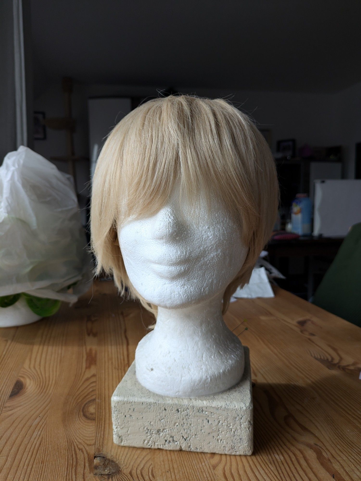 A short sandy blonde wig on a wig head, facing the front