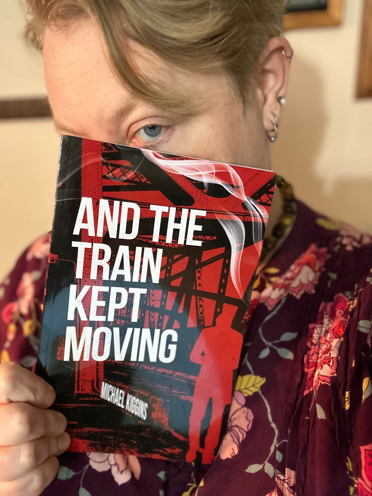 Me peeking out from behind the cover of And The Train Kept Moving by Michael Kiggins