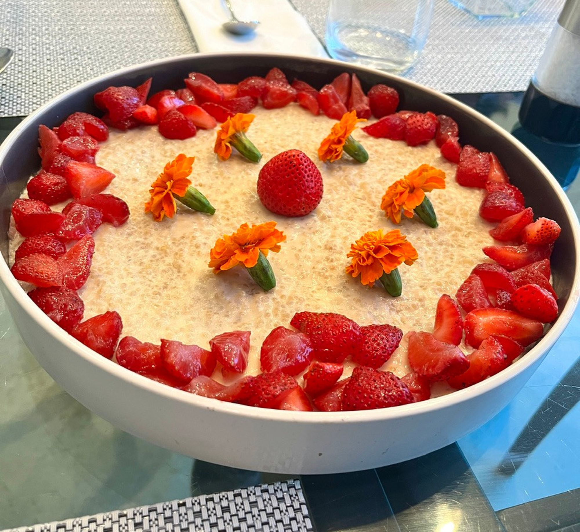 Pudding of quinoa and goat milk, with strawberries and flowers.