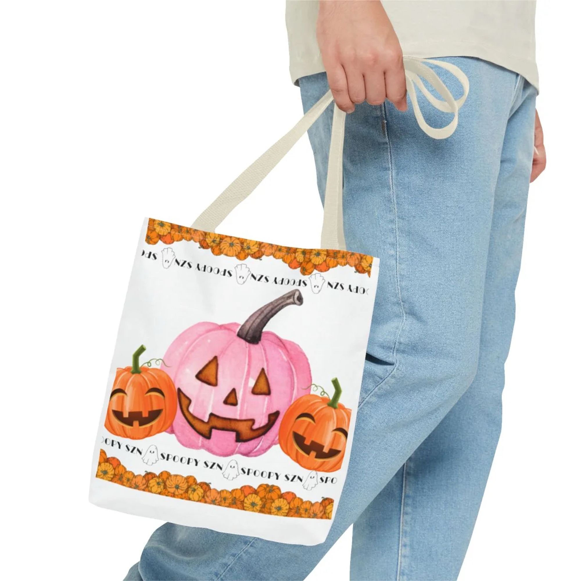 A white canvas bag with a tan strap hanging next to a pair of legs wearing light blue jeans