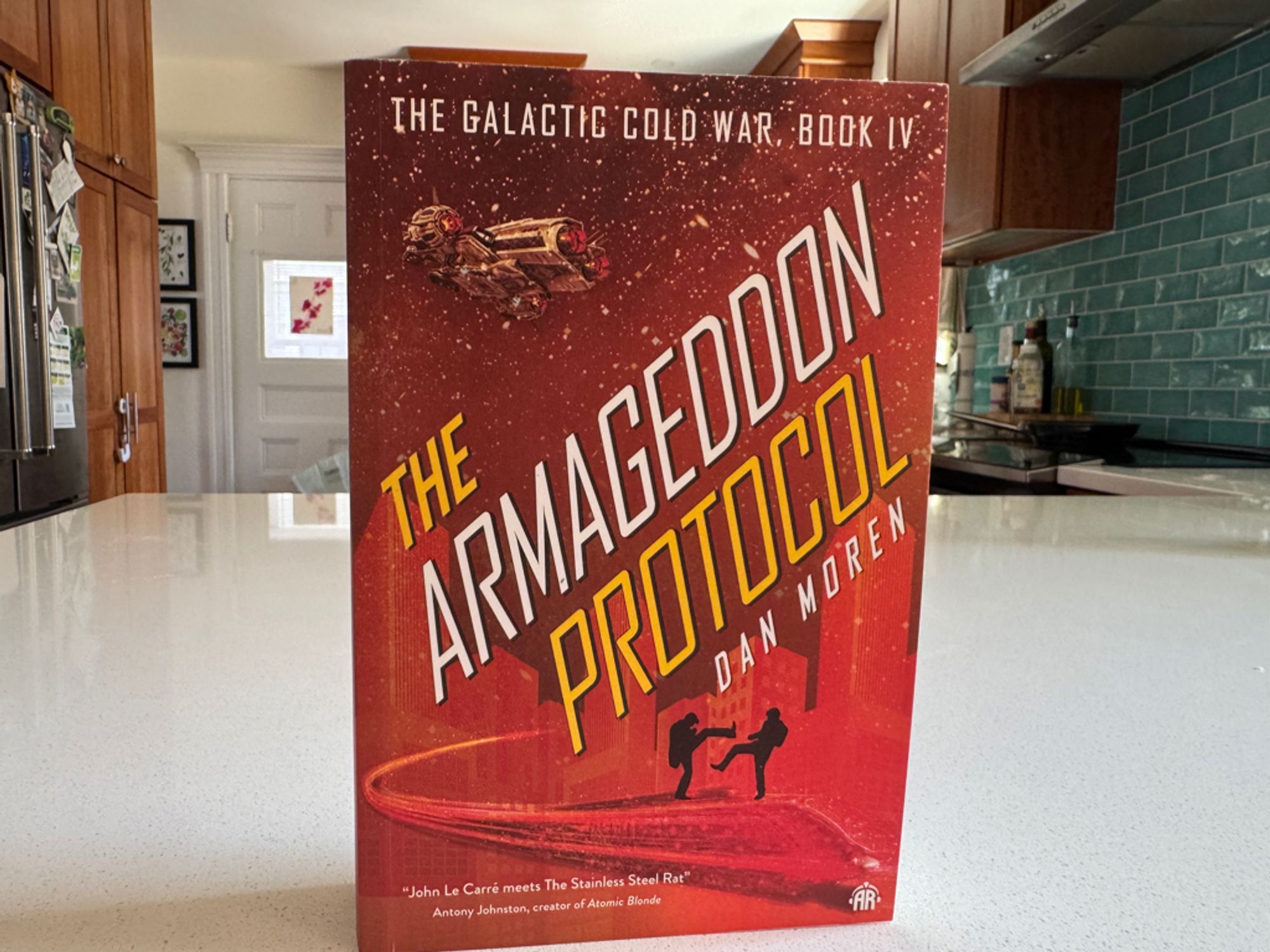 The Armageddon Protocol paperback book standing on a kitchen counter.