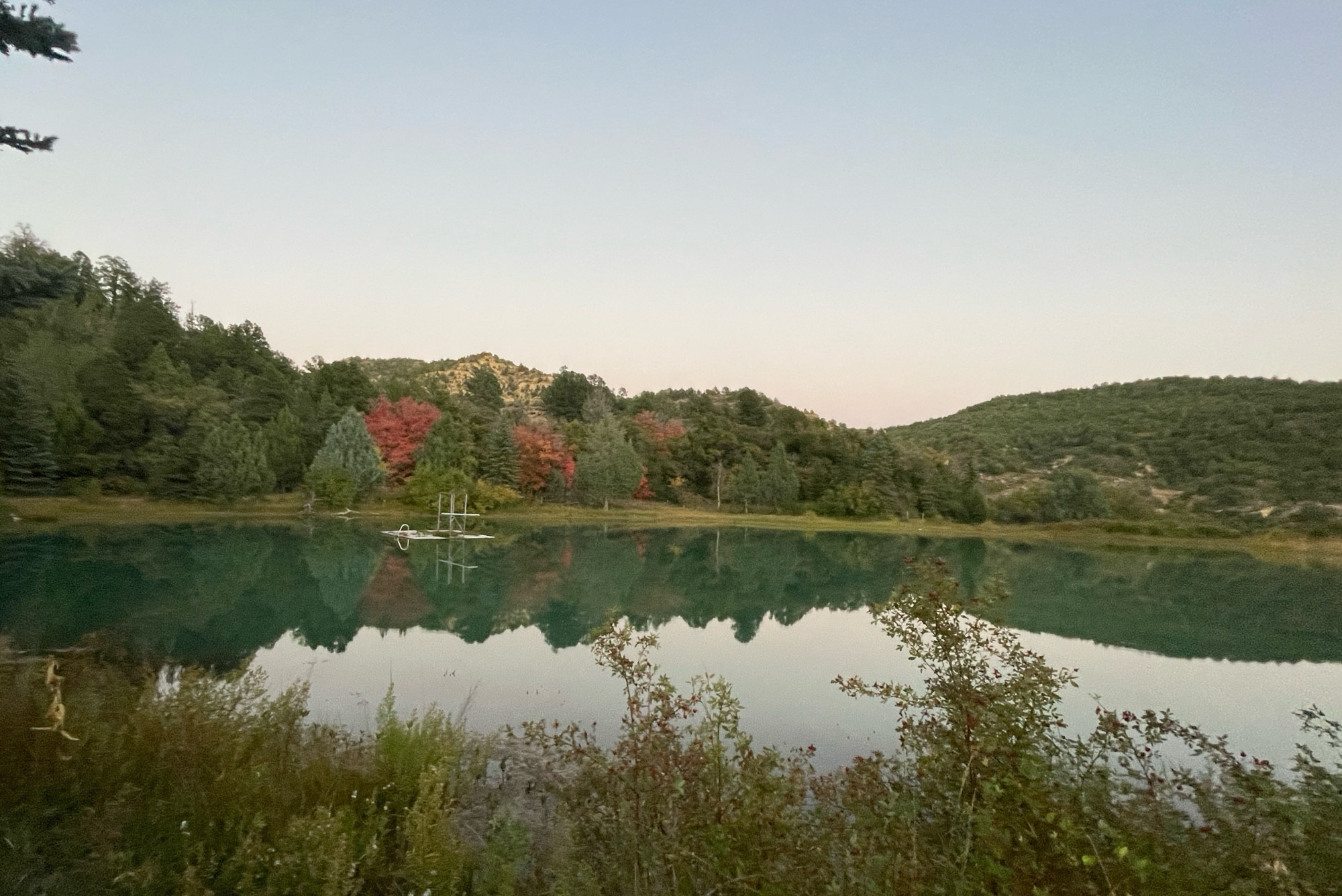 Fall colors in the trees being mirrored in a small lake.