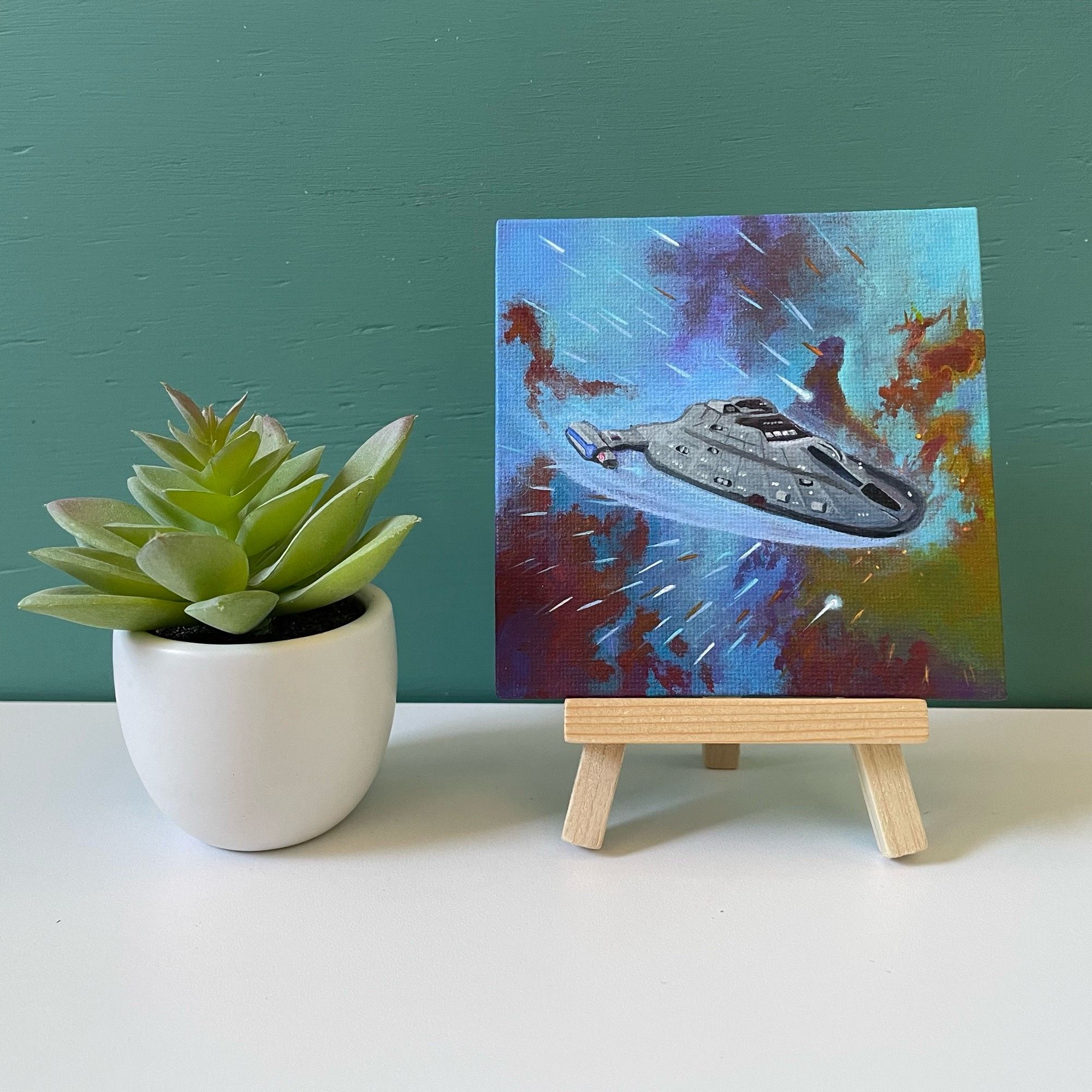 Mini painting of Voyager on easel next to fake succulent 🐡🔭