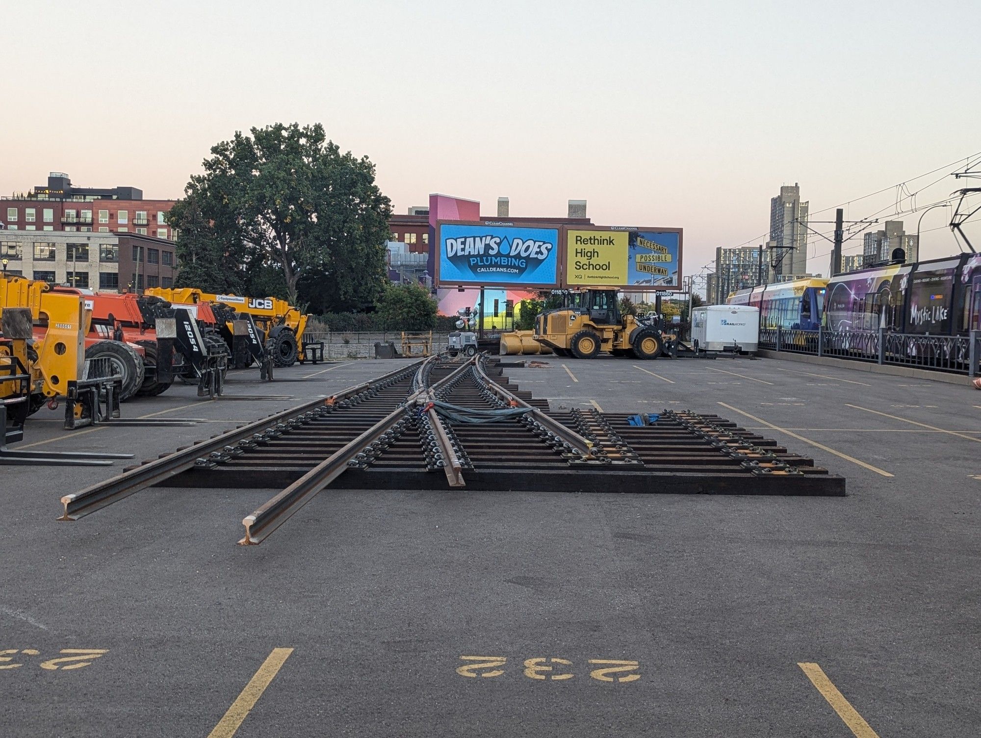 A section of replacement rails staged in a parking lot next to a light rail line.