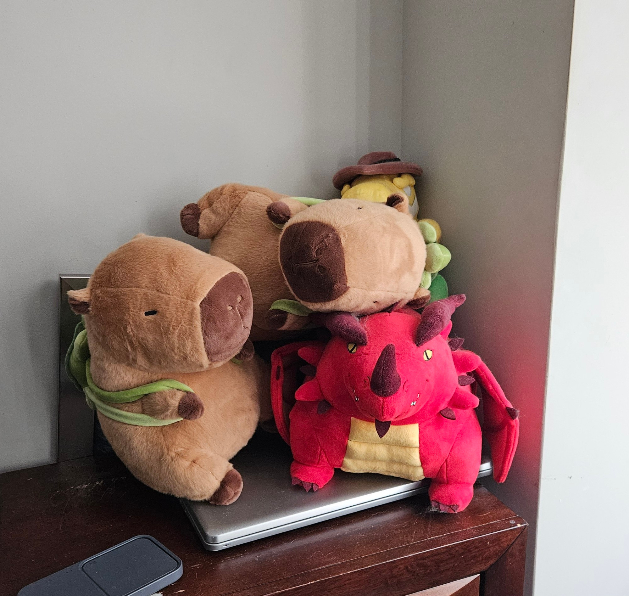 A picture of a pile of plushies. Theres one of the fat red dragon Themberchaud from the DnD movie, Gumigoo from Digital Circus, and two new capybara plushies with turtle backpacks.