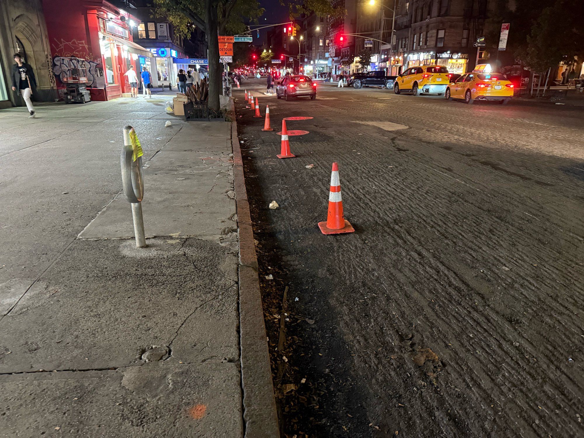 Orange traffic cones along a curb where a bike lane disappeared when pavement was milled