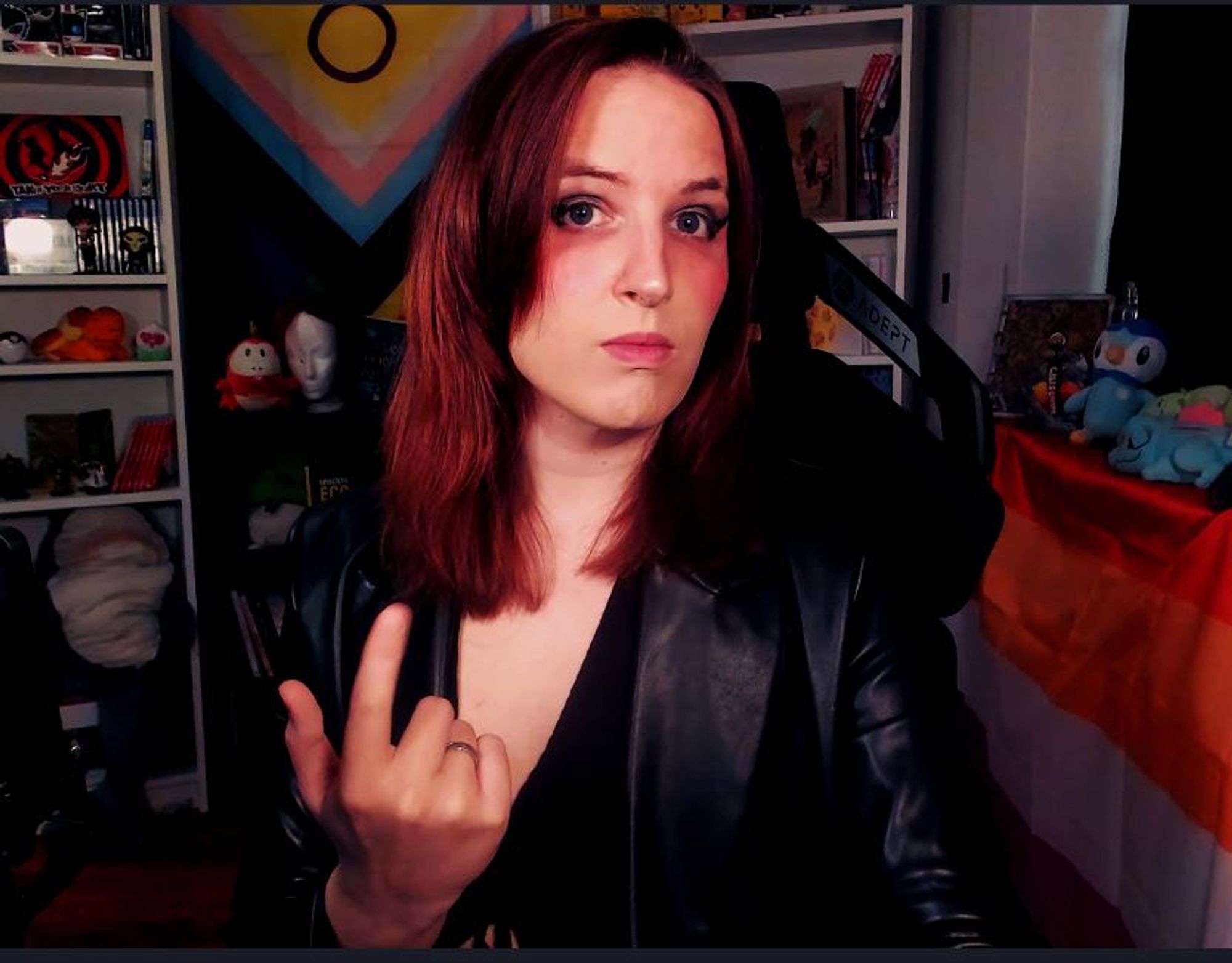 Selfie von Lili in ihrem Streamsetup. Sie guckt fordernd in die Kamera, trägt einen schwarzen Kunstleder Blazer und ein tief ausgeschnittenes Top. Die rechte Hand macht eine "Komm her" Geste.