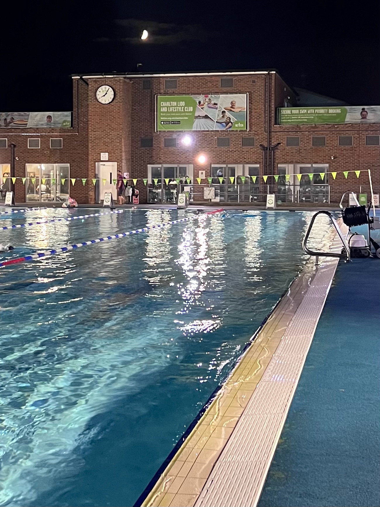 The moon rising over Charlton lido. Well lit and peaceful swimming lanes of restorative clear turquoise water.