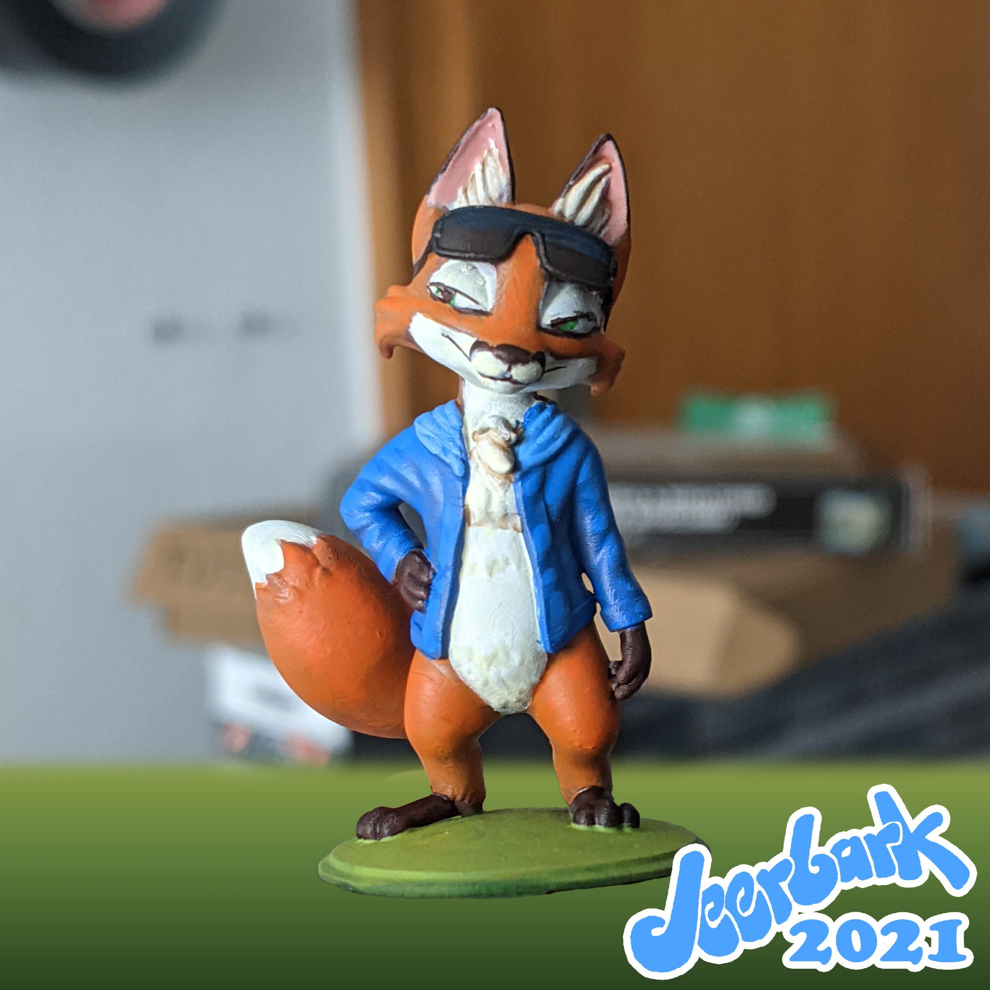 3D Printed miniature of a small anthropomorphic fox with a blue hoodie and sunglasses pushed up on his forehead