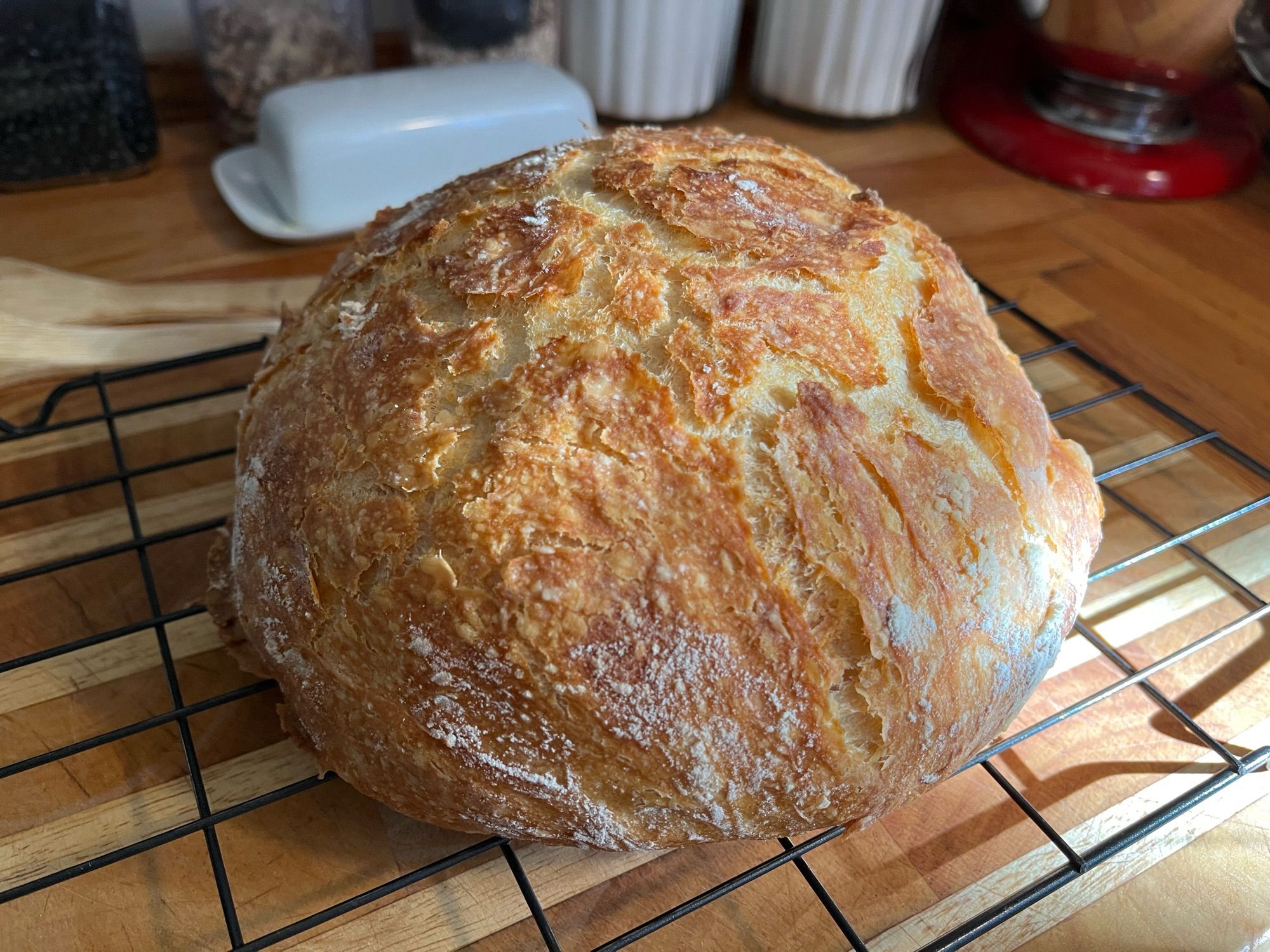 A fresh baked round loaf of bread on a cooling rack.