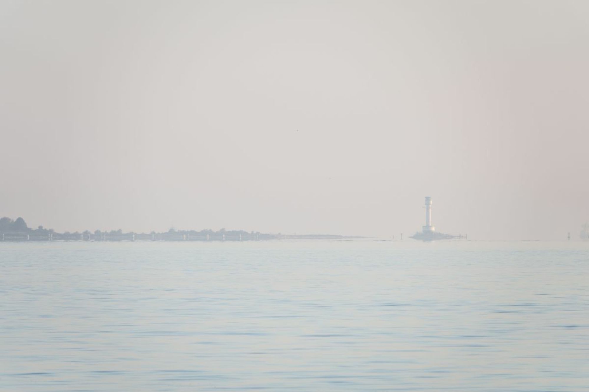 a high key picture of water and sky with a small line of land in the middle