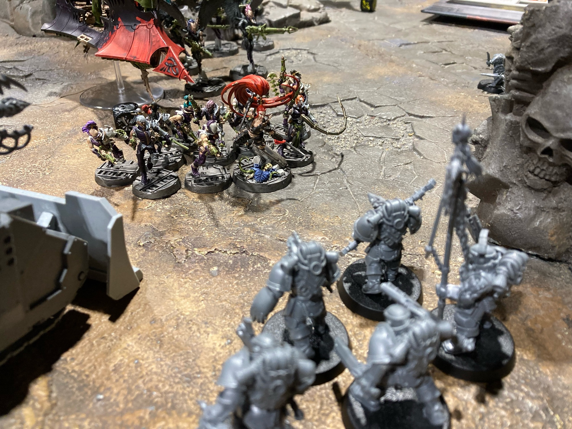 A Warhammer 40,000 battlefield with Lelith Hesperax at the head of a unit of Wyches, faced down by a tank and Chaos Space Marines.