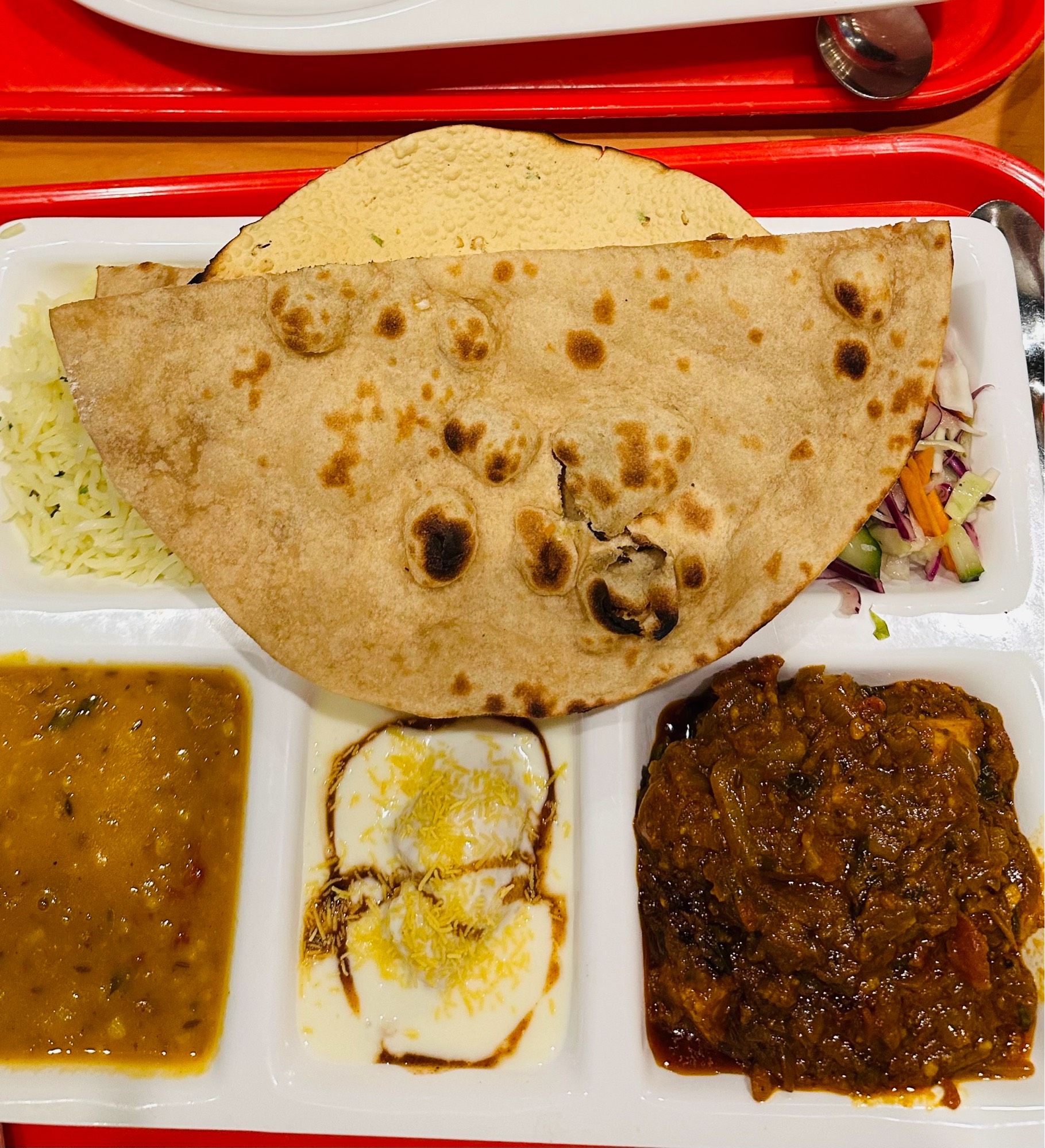 Colourful Indian food on a compartment tray. Vegetarian Bikano thali, roti, dhal, rice.