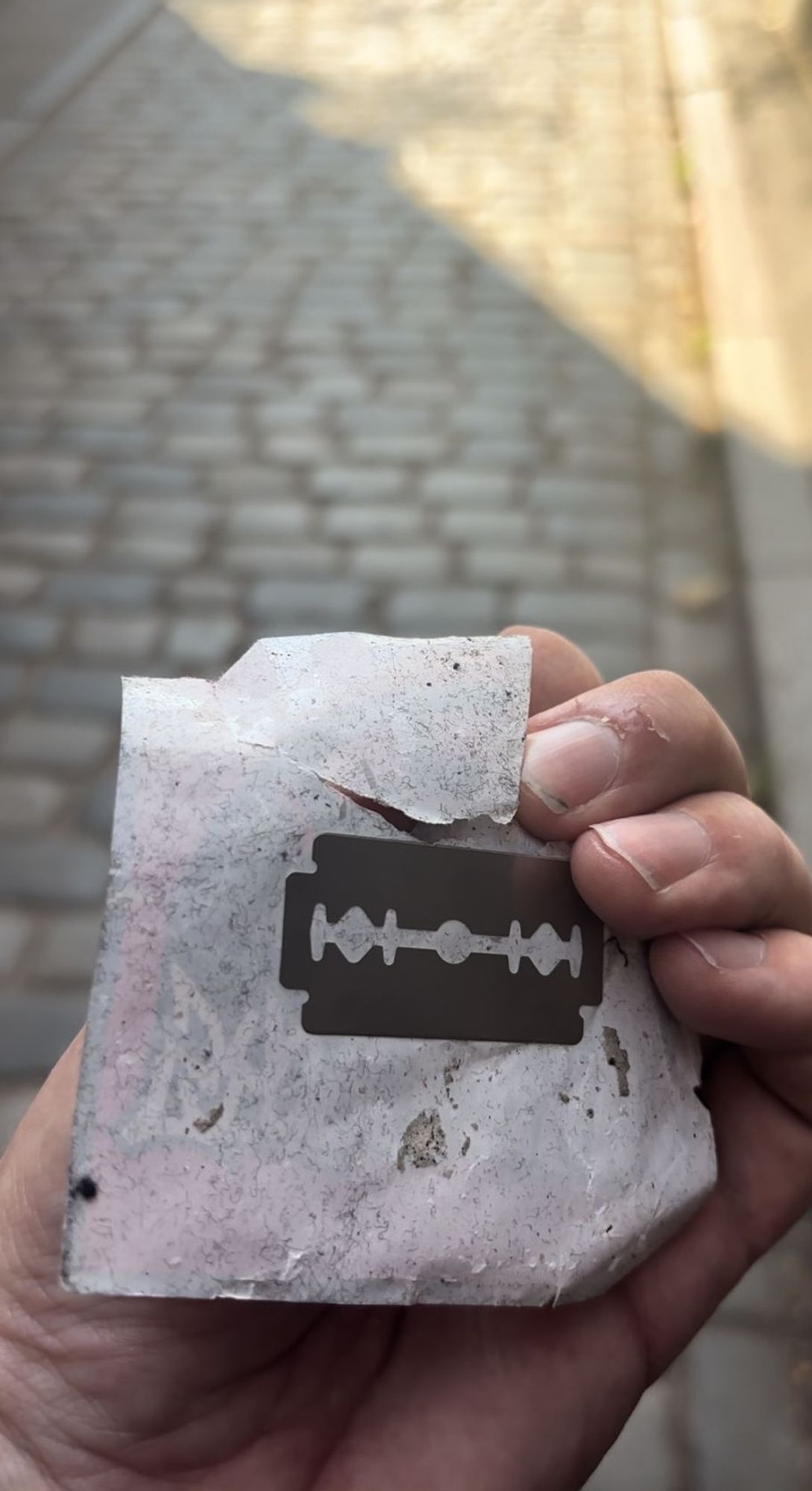 An image of a razor blade stuck to the back of a sticker advertising a neo-nazi group. Our researcher Michael found it when he attempted to remove the sticker from a wall.