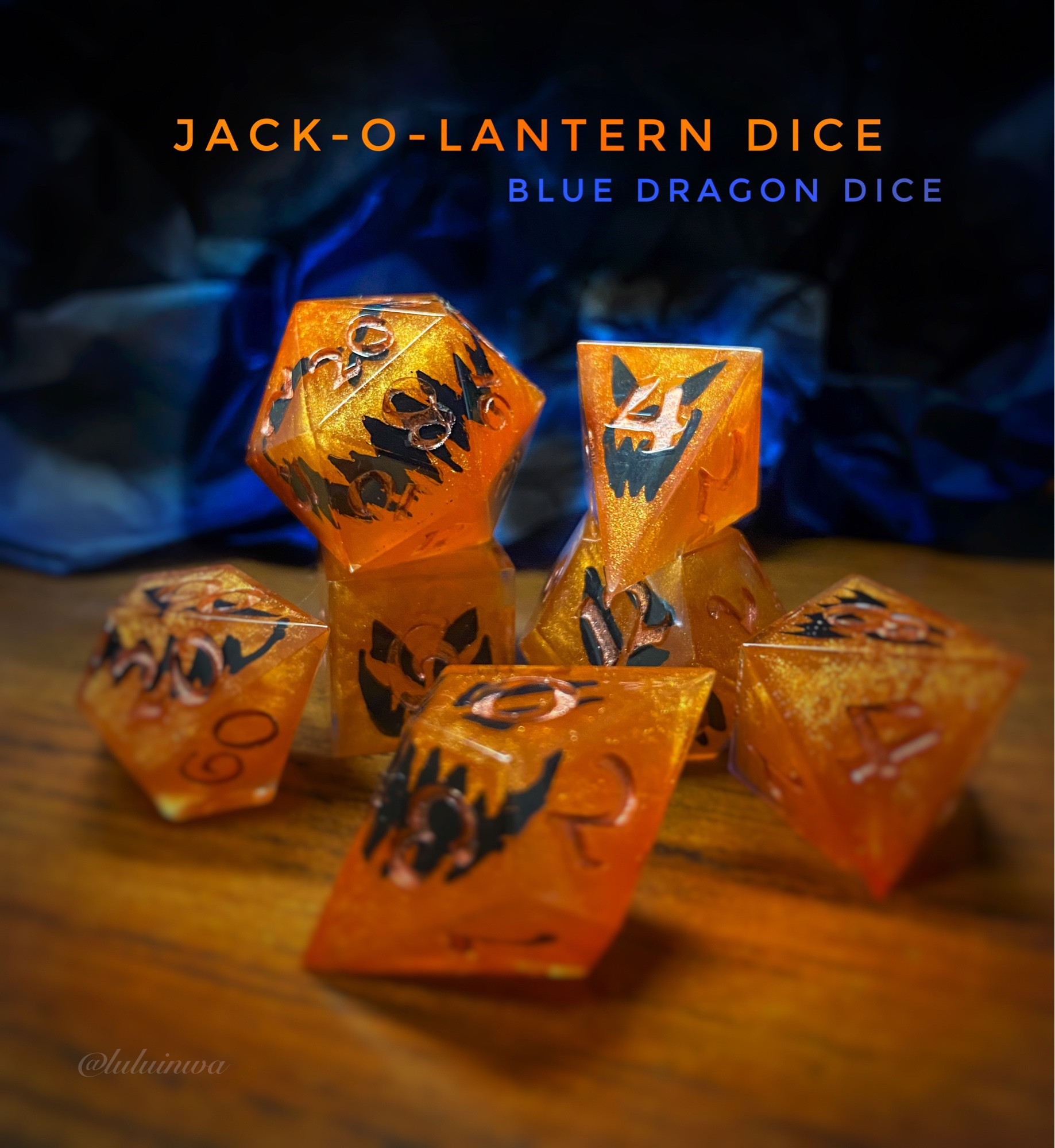 Orange dice with jack-o—lantern faced on a wooden deck with a blue black background