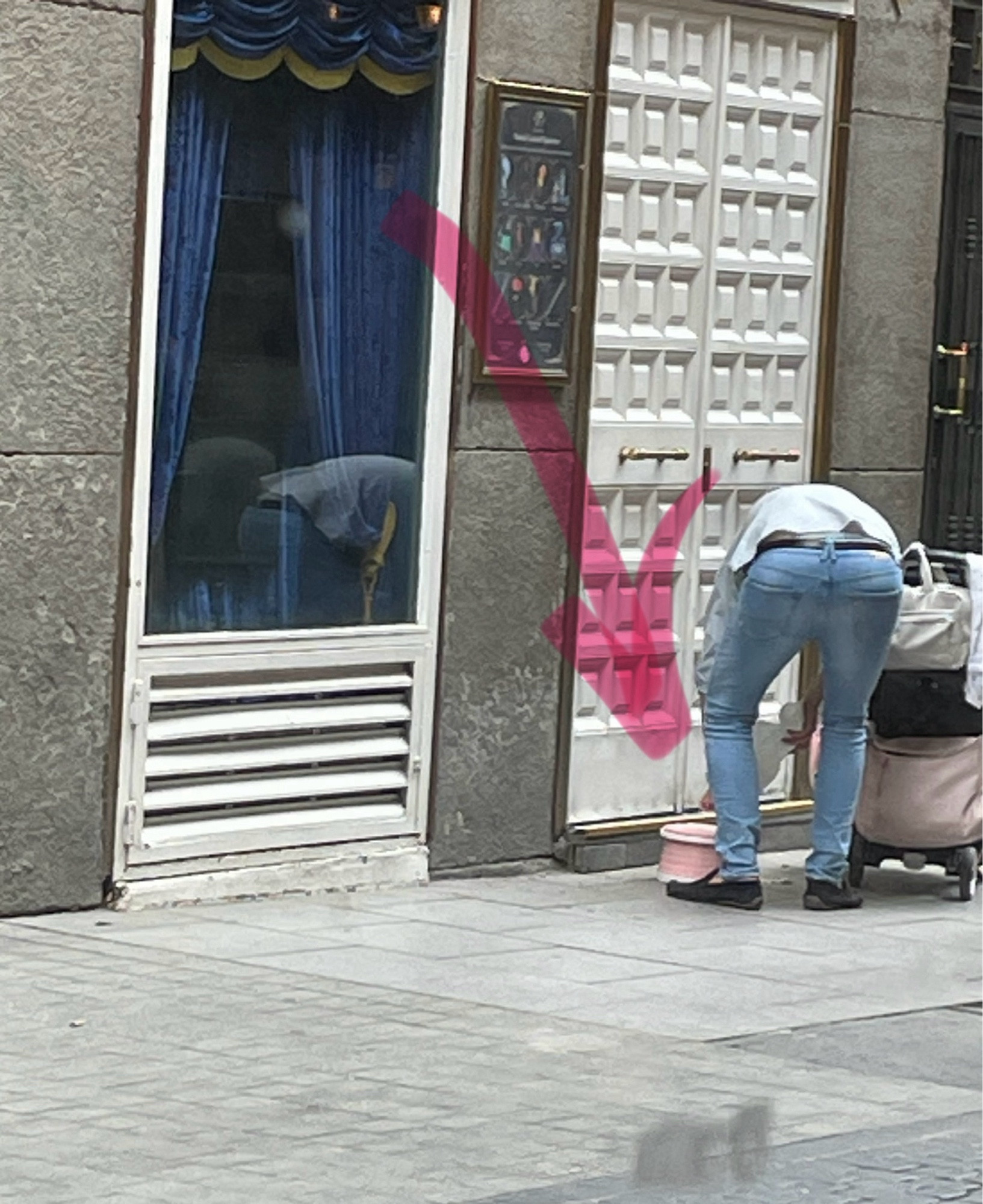 Un hombre junto a un carrito de bebé a su derecha y un retrete portátil rosa apoyado en el suelo de una calle en Madrid.