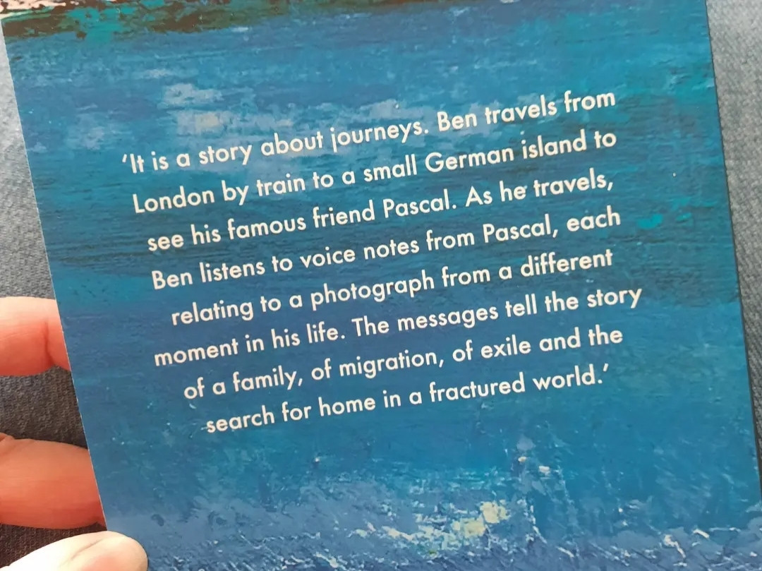 Back of the book A Dream of White Horses. Description reads: "It is a story about journeys. Ben travels from London by train to a small Geran island to see his famous friend Pascal. As he travels, Ben listens to voice notes from Pascal, each relating to a photograph from  different moment in his life. The messages tell the story of a family, of migration, of exile and the search for home in a fractured world."