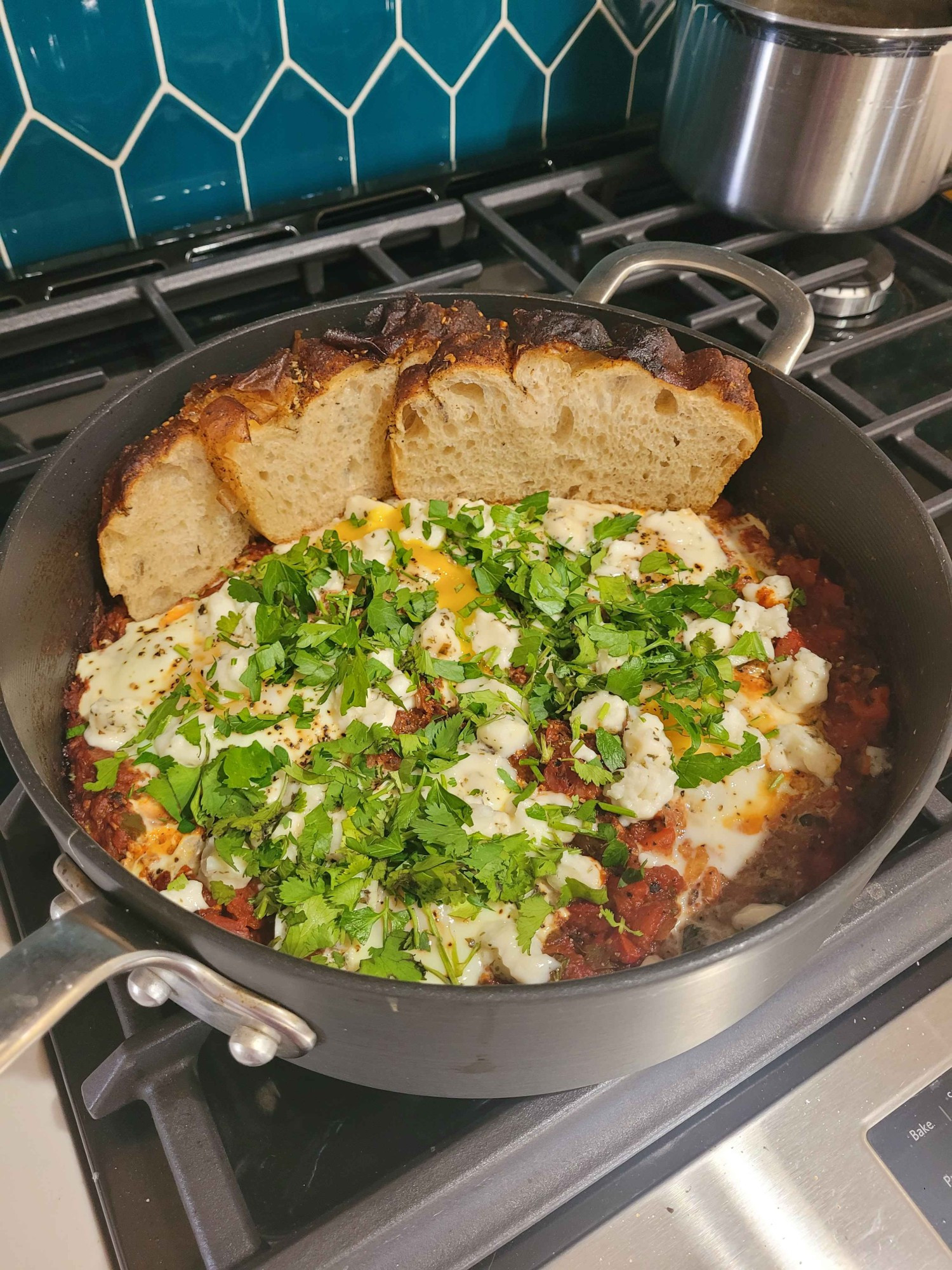 A picture of a pan containing a shakshouka dish I made with some sliced bread to the side.