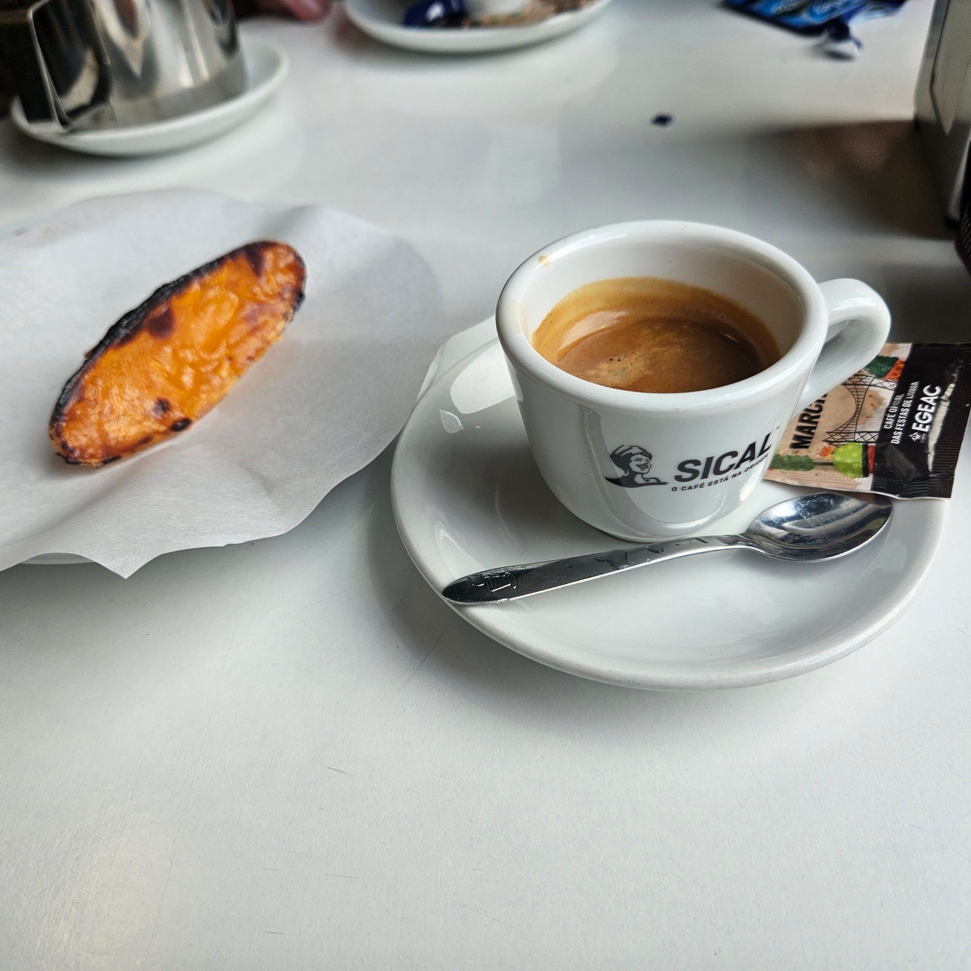 A coffee and a cigar-shaped Portuguese egg pastry.