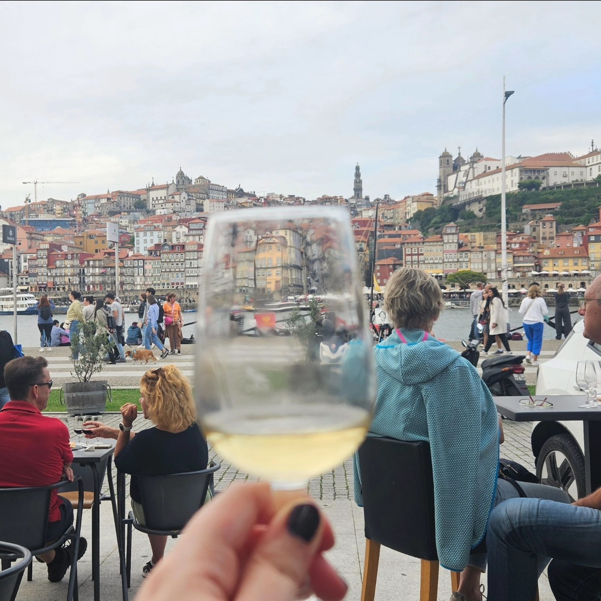 I am holding a glass of white port up in front of the Douro river. I am in Gaia, across the river from Porto.