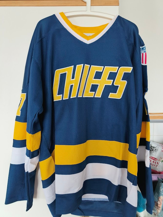 A blue hockey jersey with yellow and white horizontal stripes. On the shirt in large golden letters is written CHIEFS.