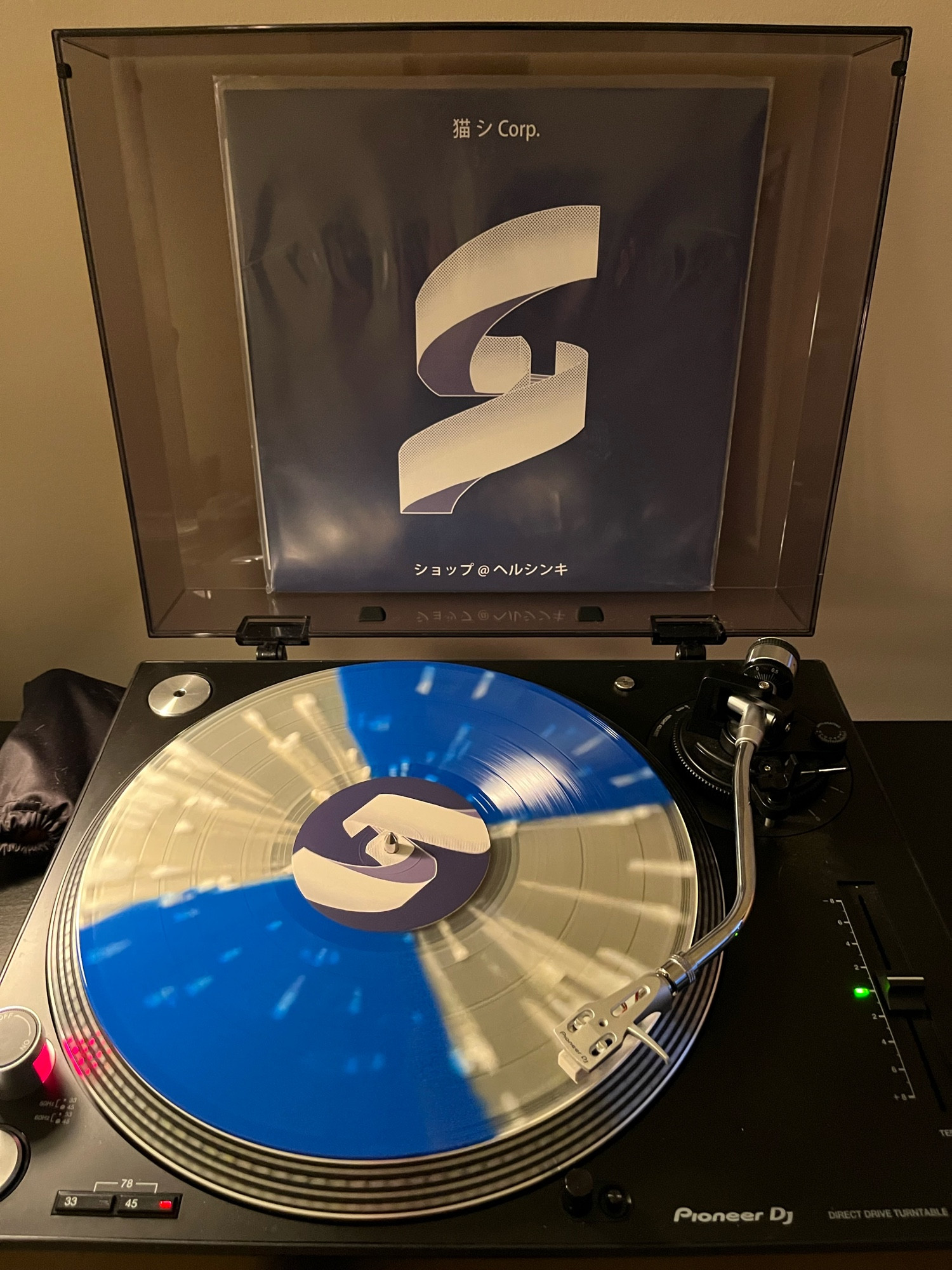 New Cat Systems Corp vinyl playing on my turntable. The album jacket depicts a clip art version of a spiral staircase. The vinyl is a mixture of a blue and cloudy white hemispheres with white splatters.