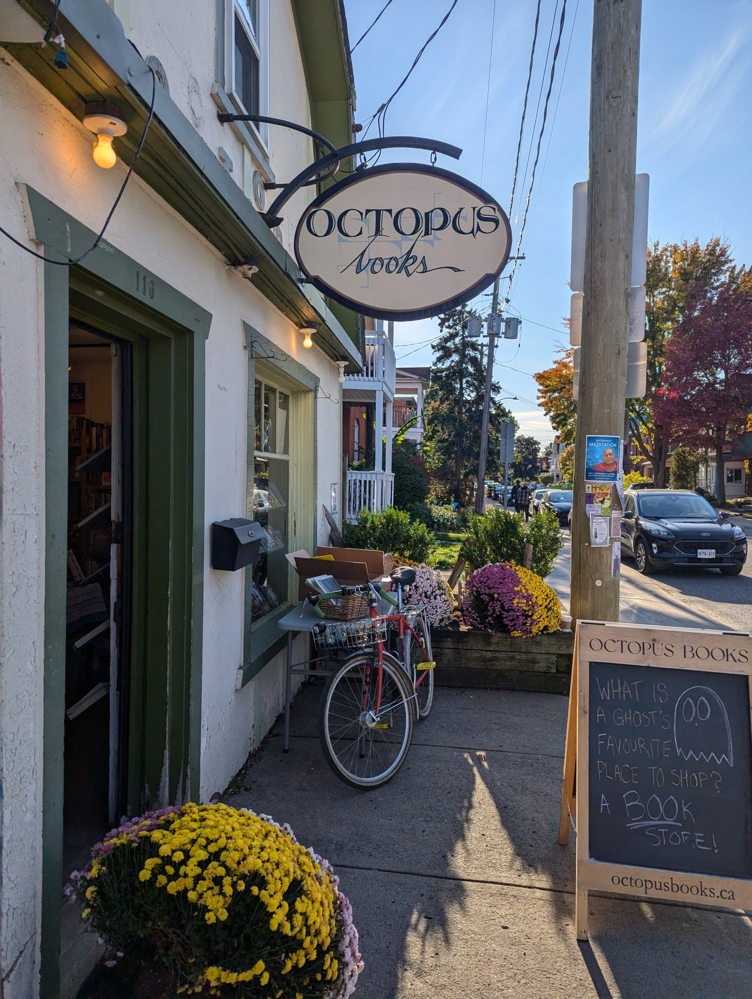 A red bike with a front basket, viewed head on, with the handlebars/for turned to the right, in front of a bookstore. The Octopus Books sign is hanging overhead.