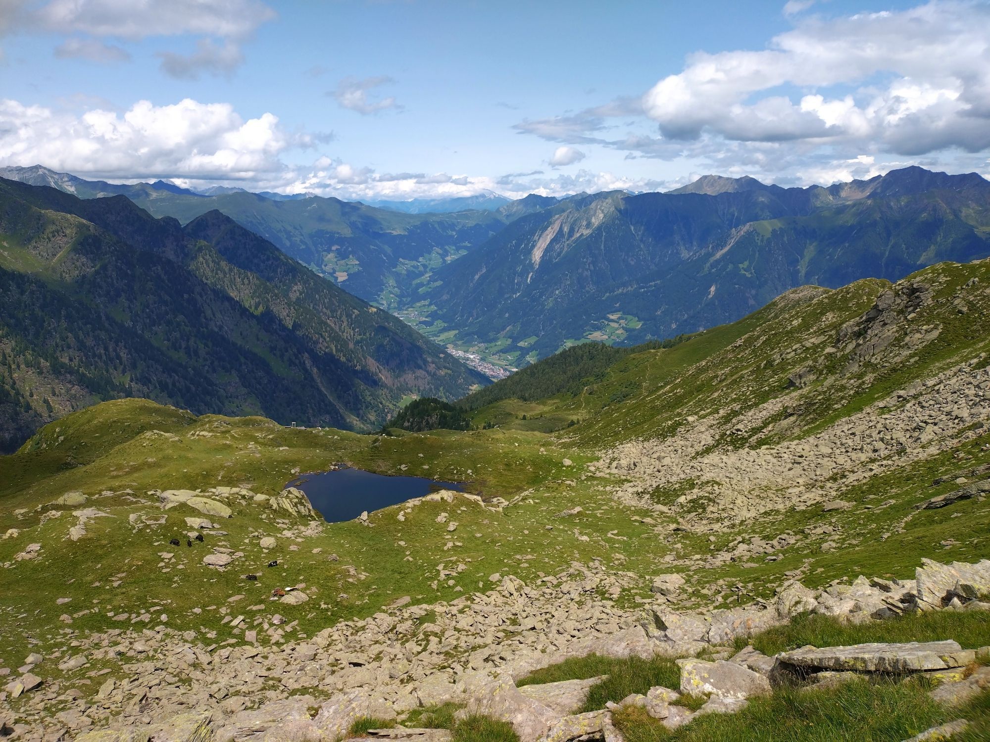 View from a mountain peak down to a small lake and the valley with a small village.