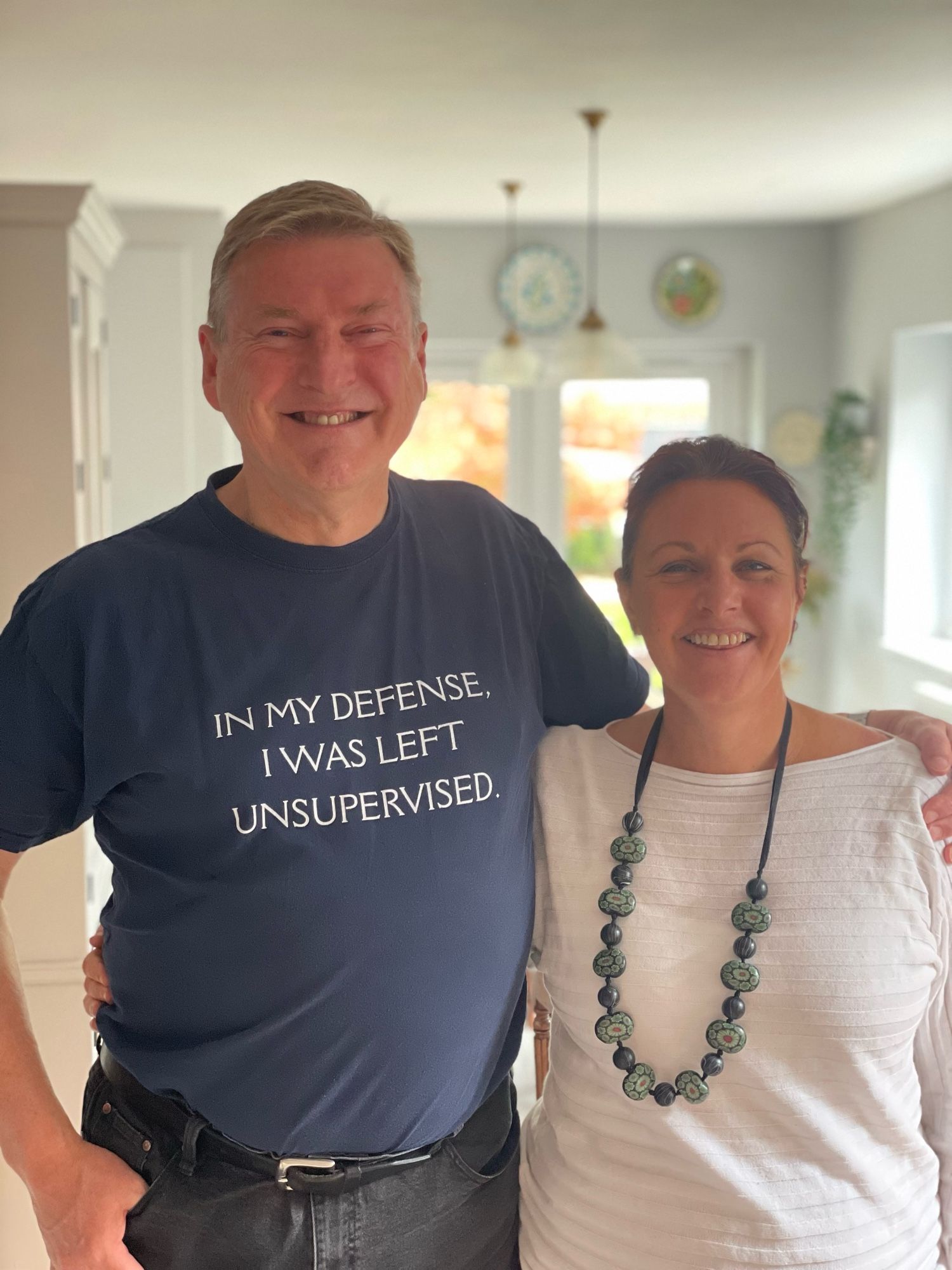 Two people smiling, one wearing T-shirt that says ‘in my defence I was left unsupervised’