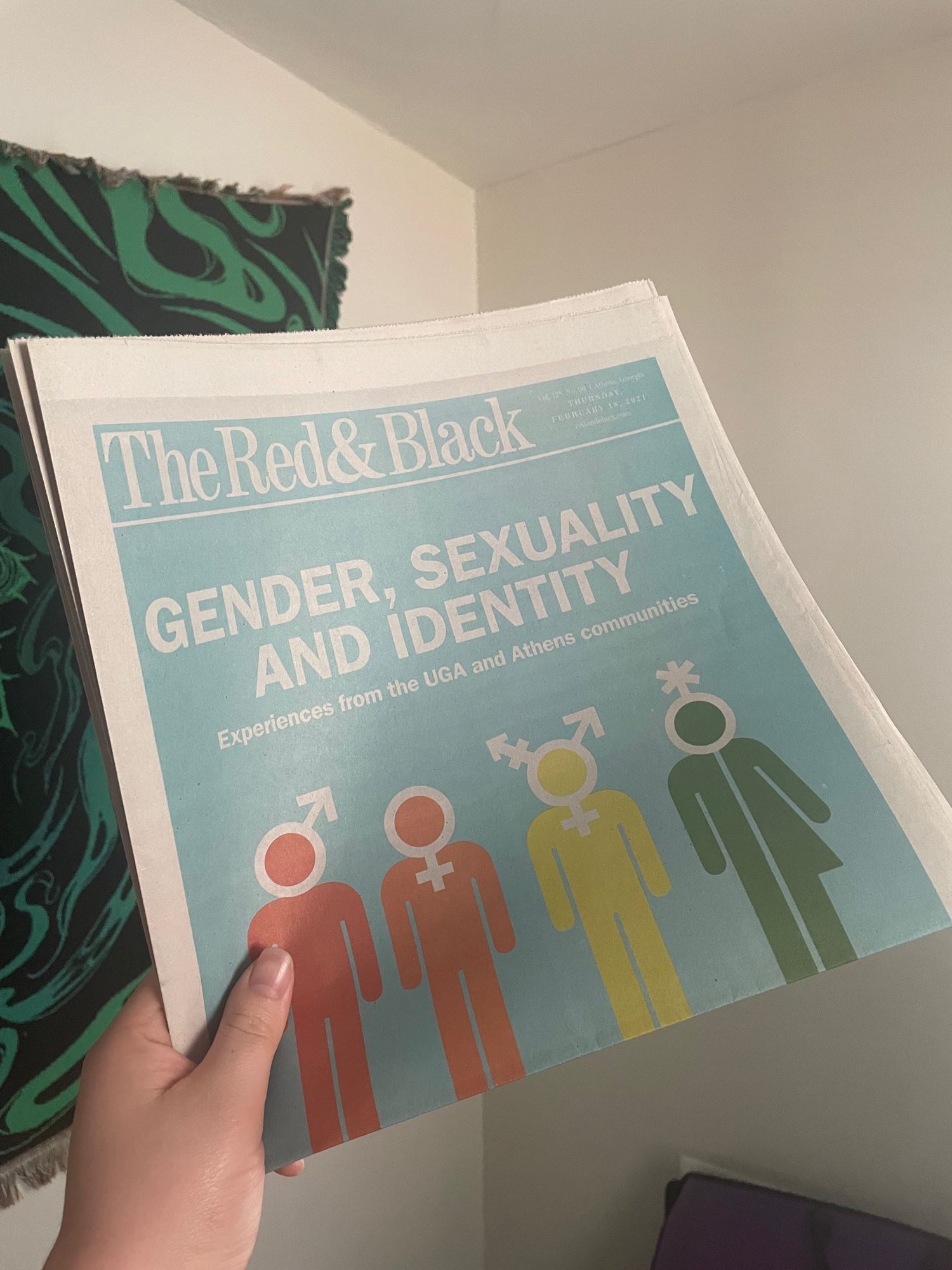 A hand holding up a folded newspaper from The Red & Black, the independent student-run newspaper in Athens, Georgia. The headline reads “Gender, Sexuality and Identity” with a subhed that reads “Experiences from the UGA and Athens communities”

It has a light blue background with silhouettes of people in red, orange, yellow and green, with white gender symbols of male, female, trans and nonbinary respectively.