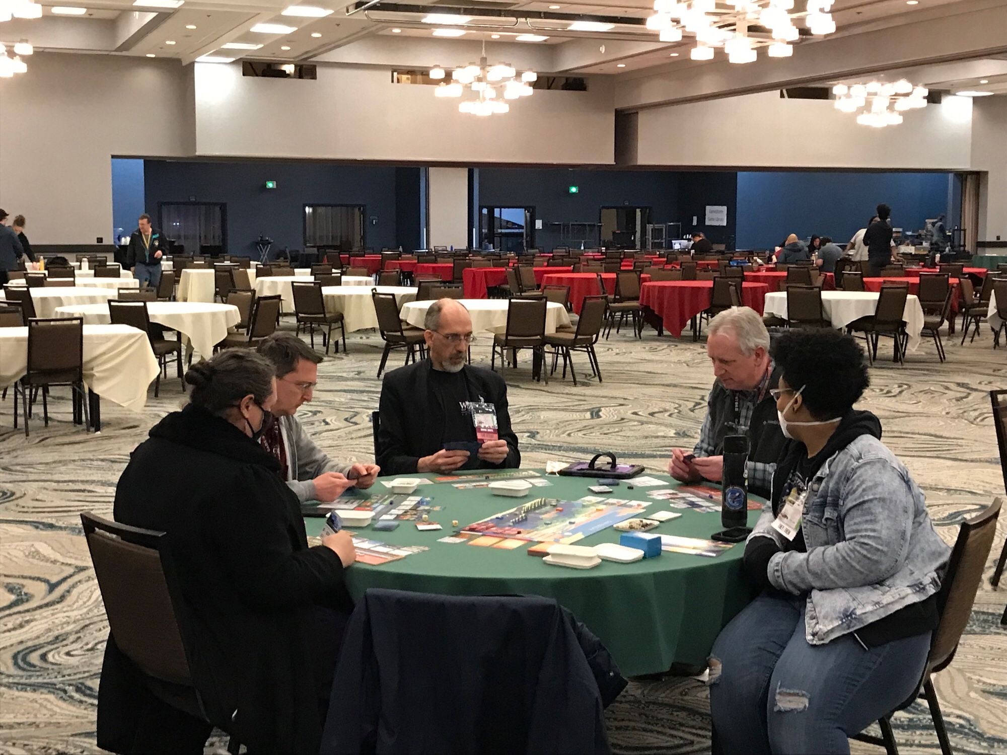 Photo of five people seated around a round table playing Daybreak board game