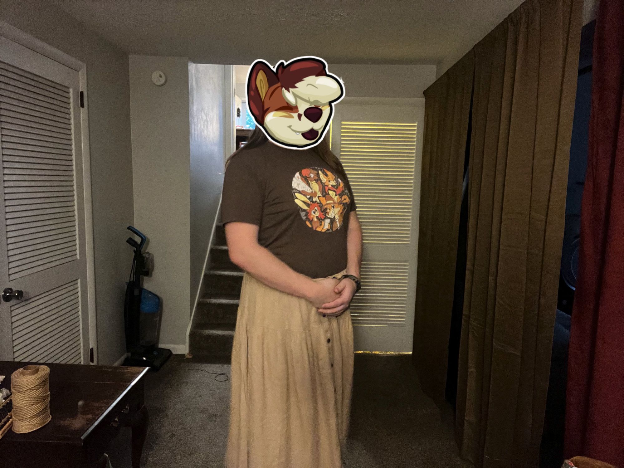 A picture of yours truly for today, with a Lufty "bliss" sticker obscuring my IRL face. The top is my brown FWA 2023 con t-shirt, with a khaki colored full length skirt below.