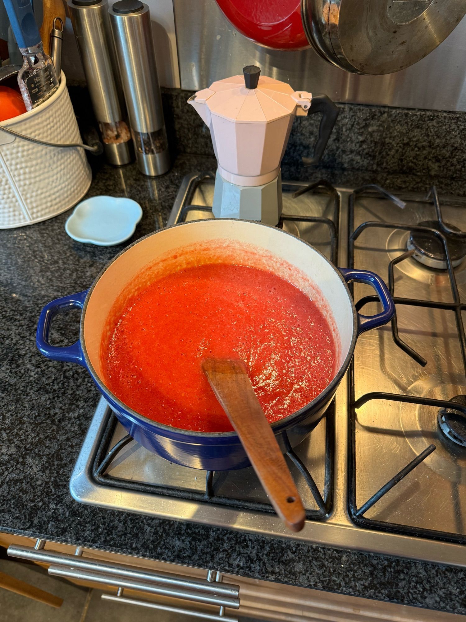 An enamelled iron pot full of puréed homegrown tomatoes simmers gently on a hob.