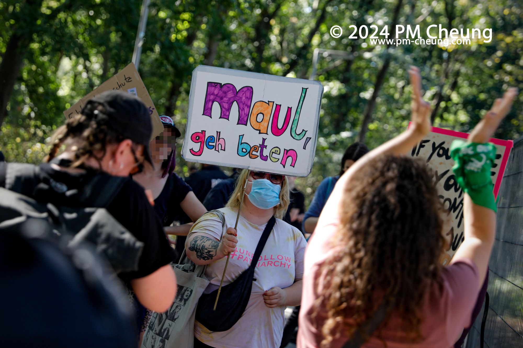 Eine Gegendemonstrantin in der Nähe des Brandenburger Tors, mit einem Schild, worauf "Maul, geh beten" zu lesen ist.