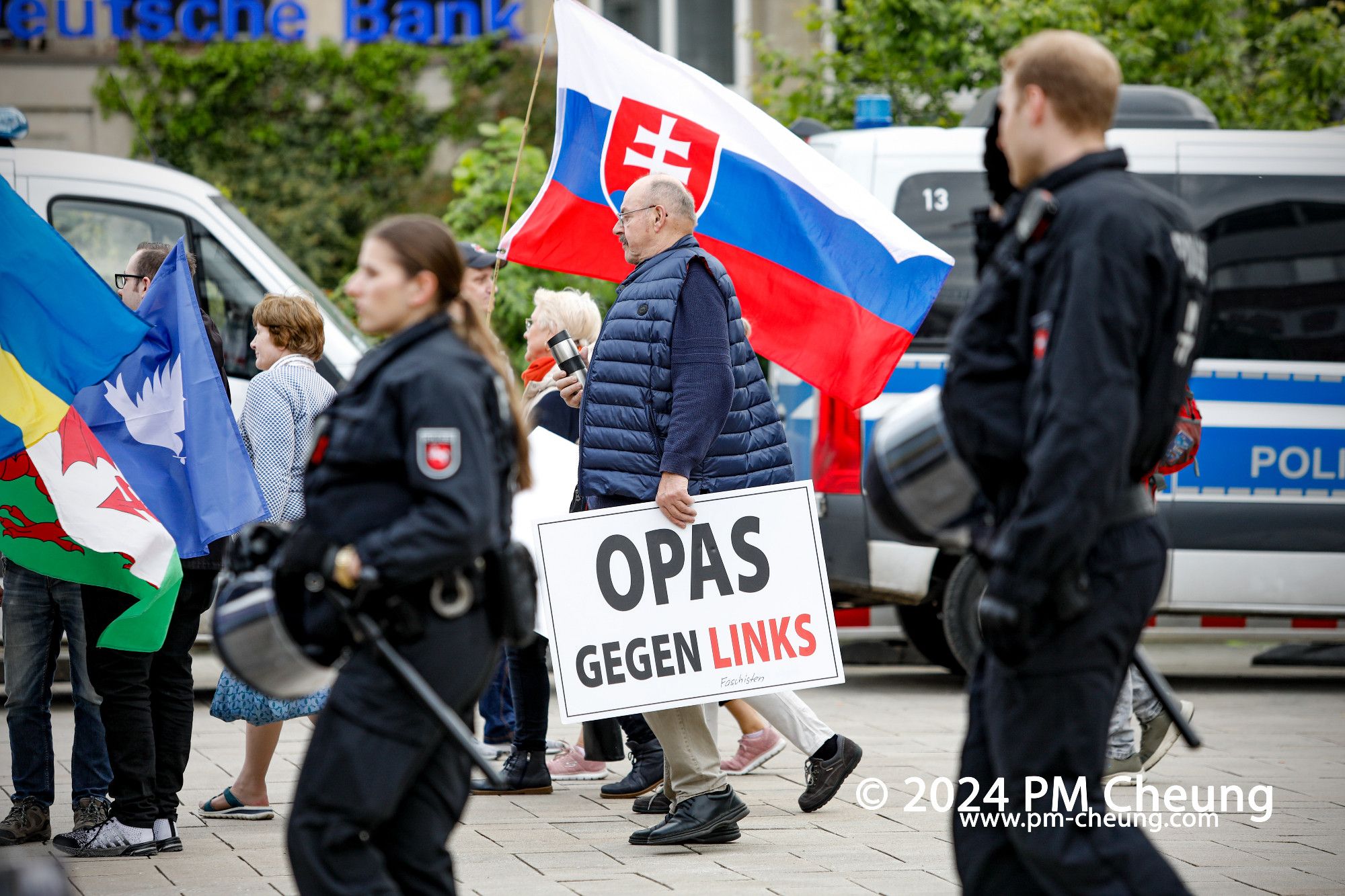 Ein Teilnehmer des Aufmarsches trägt ein Schild mit der Aufschrift "Opas gegen links". Dahinter ist eine Fahne der Slowakei zu sehen.