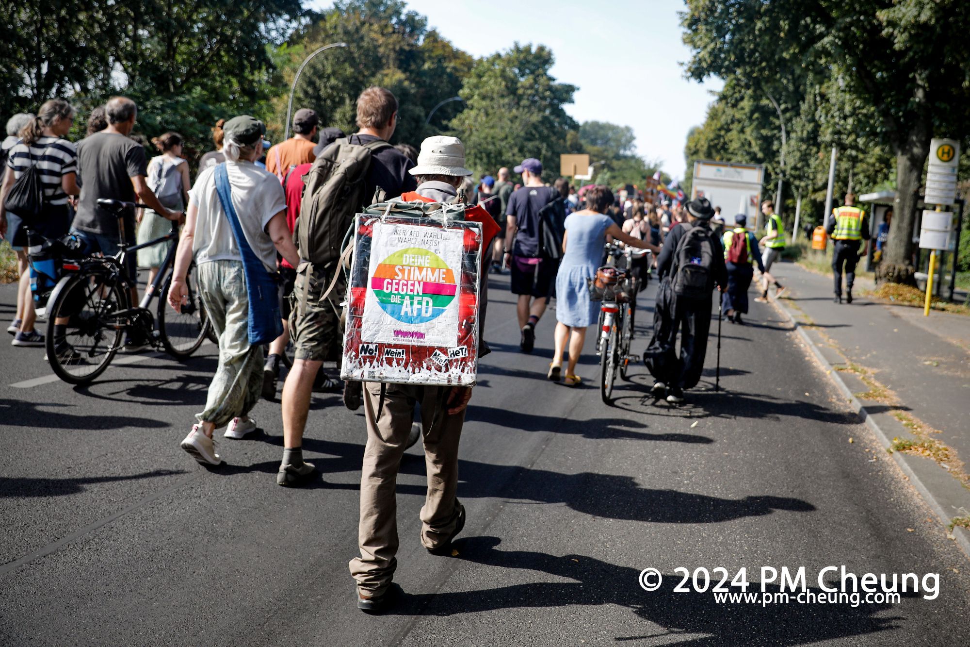 Ein Teilnehmer der Demonstration trägt auf dem Rücken ein Schild, worauf "Deine Stimme gegen die AfD" zu lesen ist.