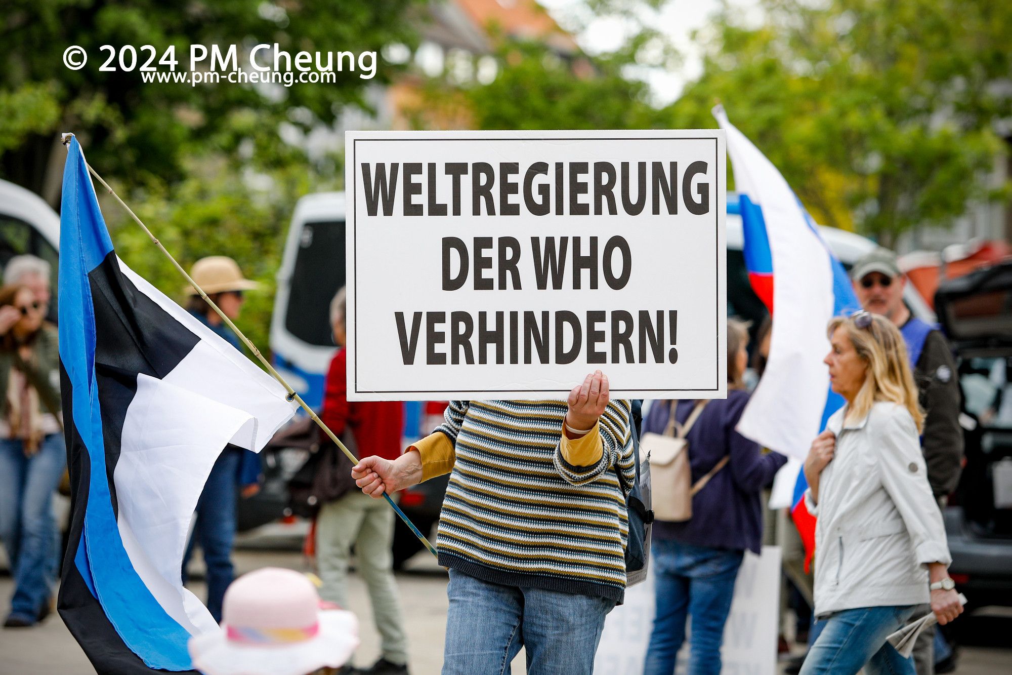 Eine Demonstrantin mit einem Schild, auf der "Weltregierung der WHO verhindern" zu sehen ist.