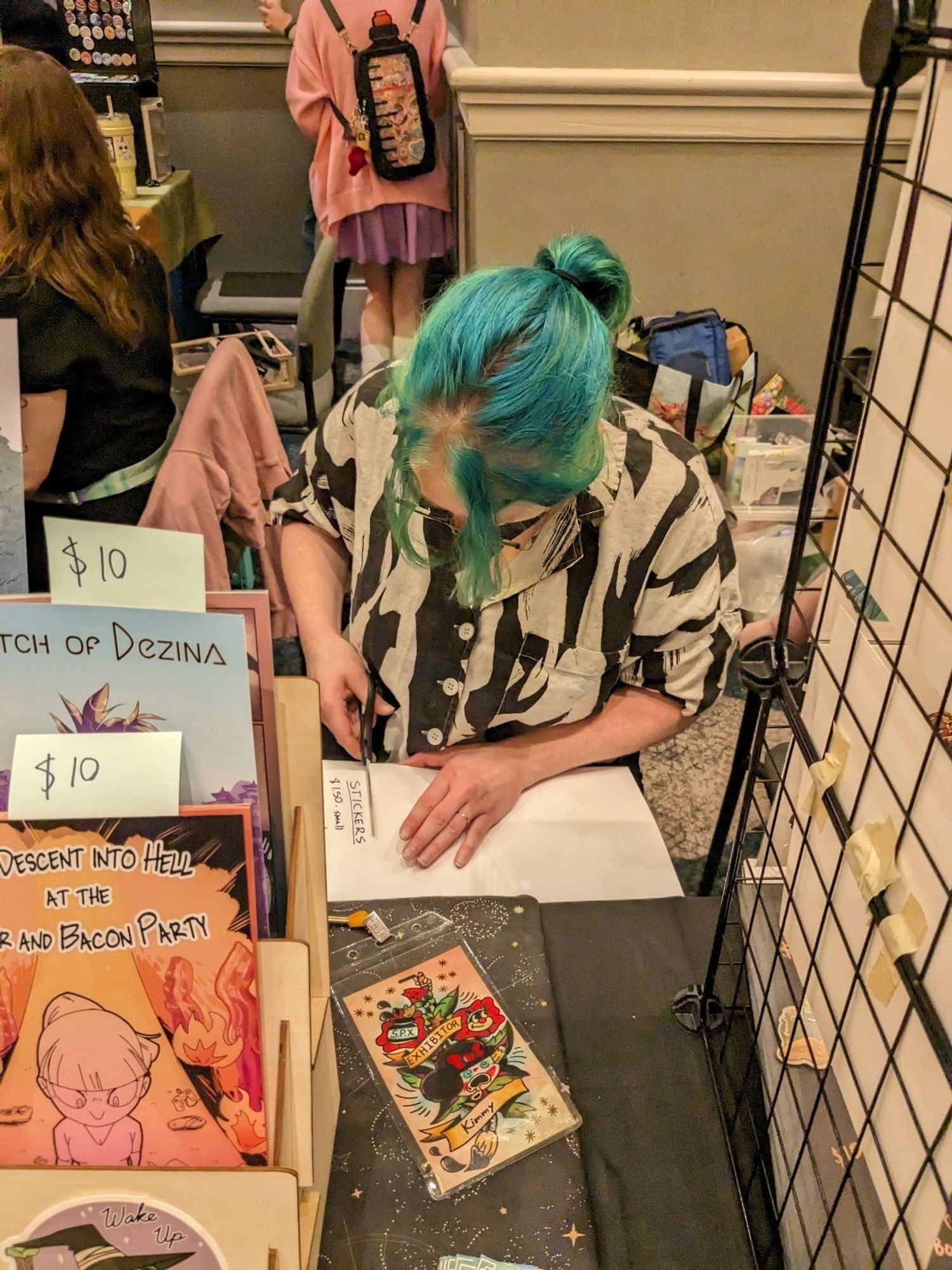 Photograph of me cutting out price sheets at an artist alley table