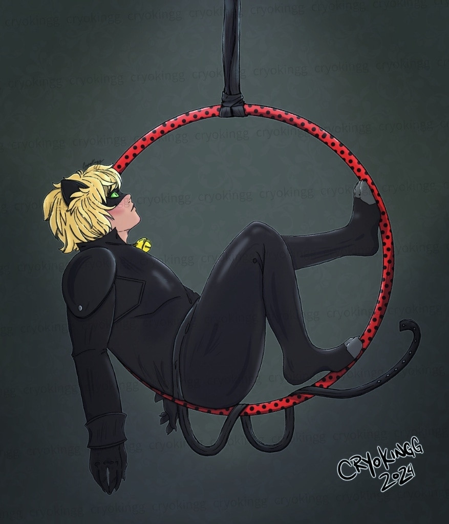 A blonde boy in a black, cat suit on a red and black spotted aerial hoop.