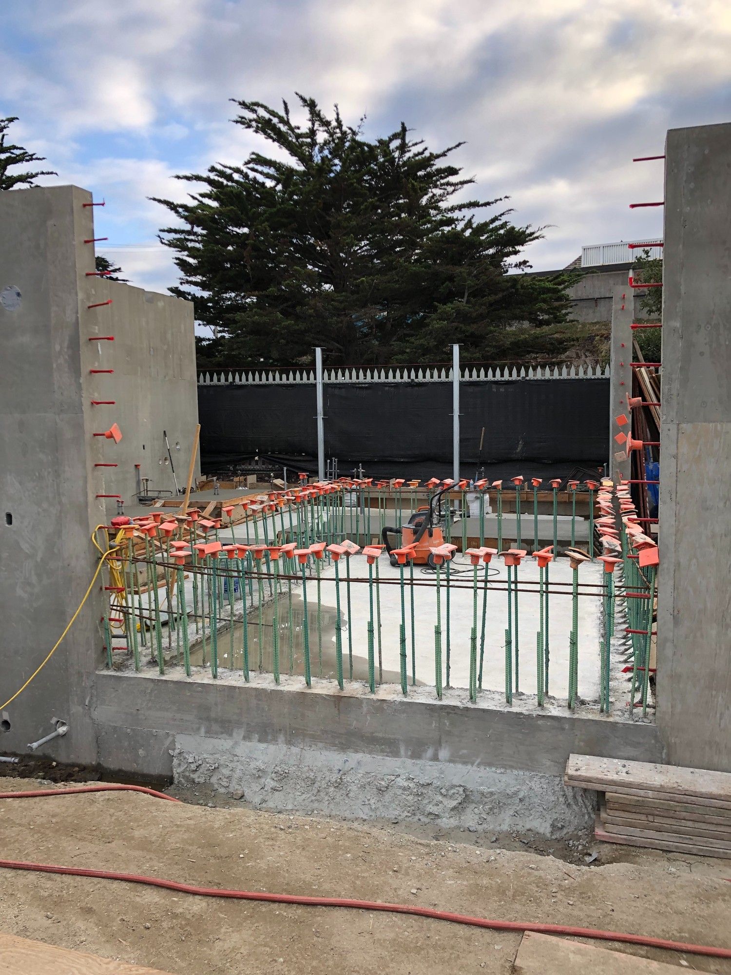 View of the concrete tank rebar in progress of construction at the Sea Otter Rehabilitation Facility. Orange and green construction materials line the gray concrete tank.