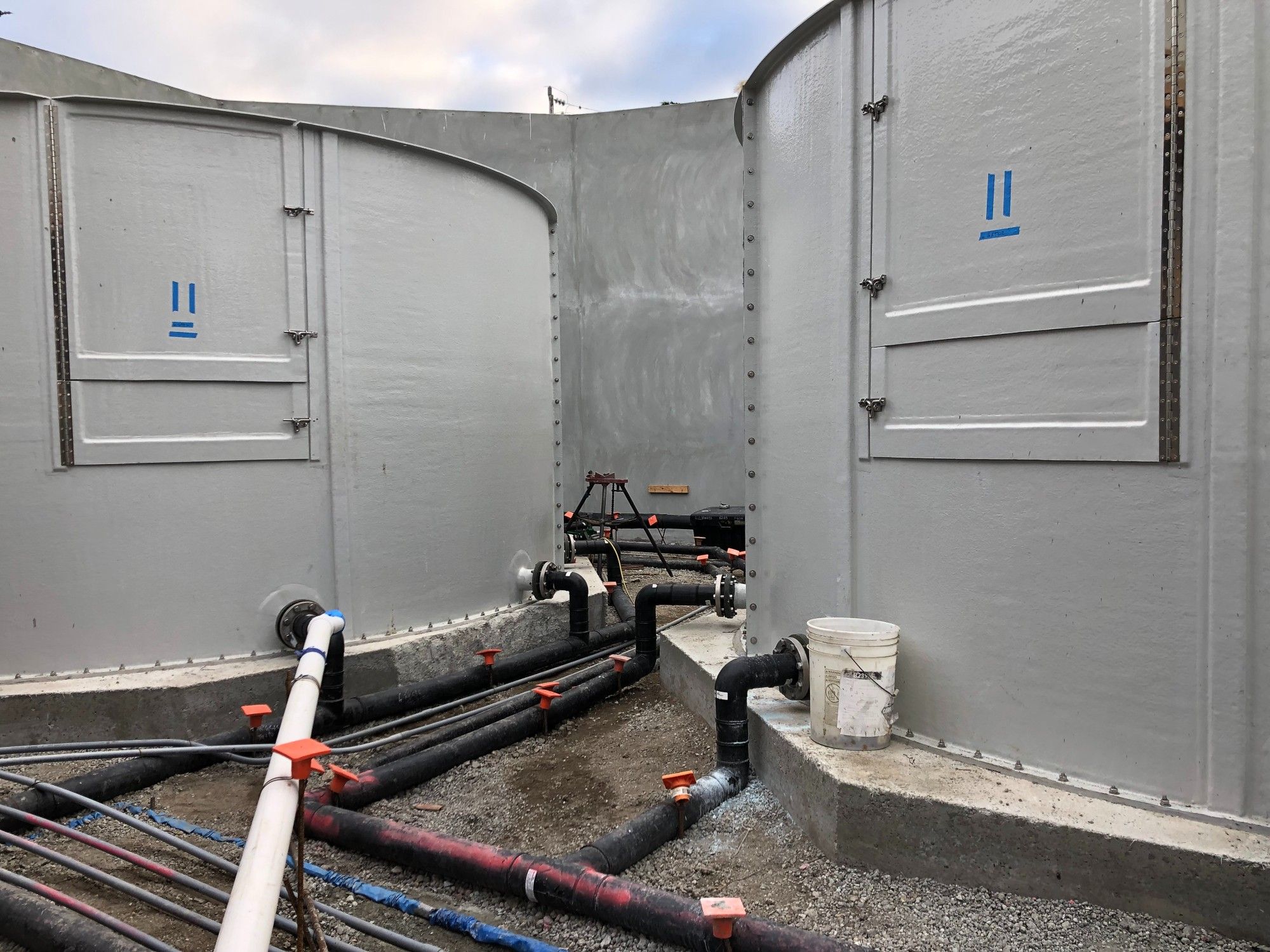 View of the Sea Otter Rehabilitation Facility in construction. Two large, gray tanks are shown with pipes below running from the tanks.